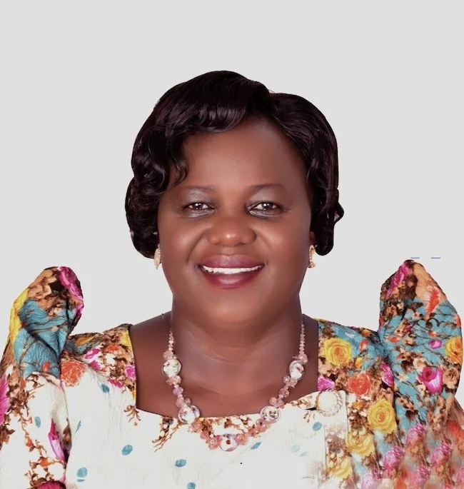 Smiling woman with colorful blouse and necklace.