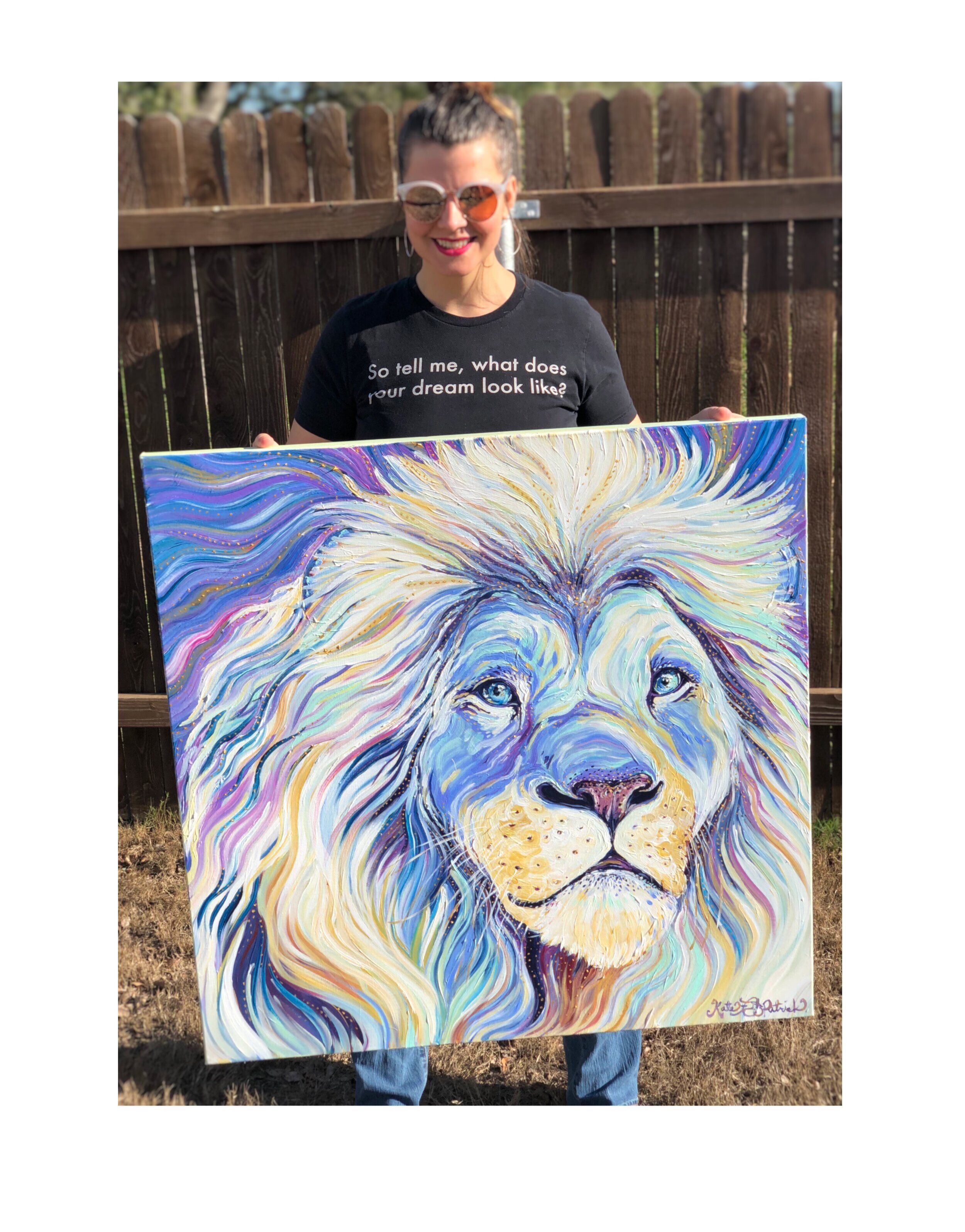 Kate, a white woman wearing sunglasses, holds the white Lion painting.