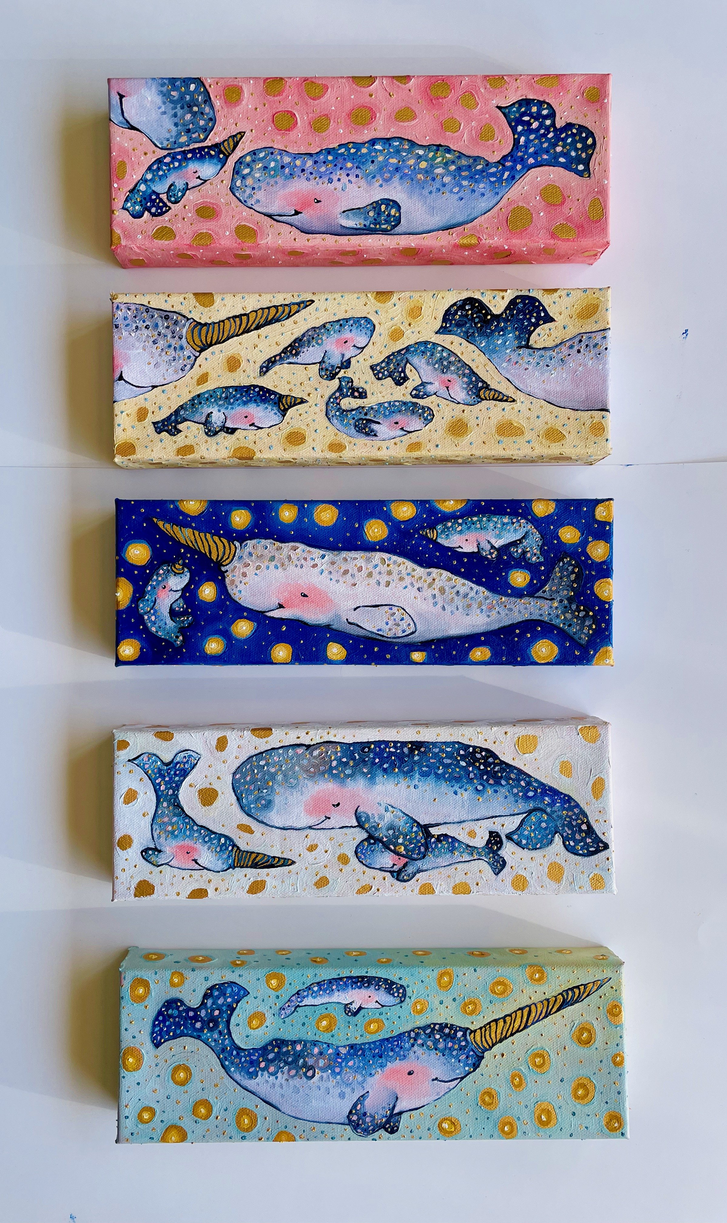 five narwhal family paintings displayed vertically