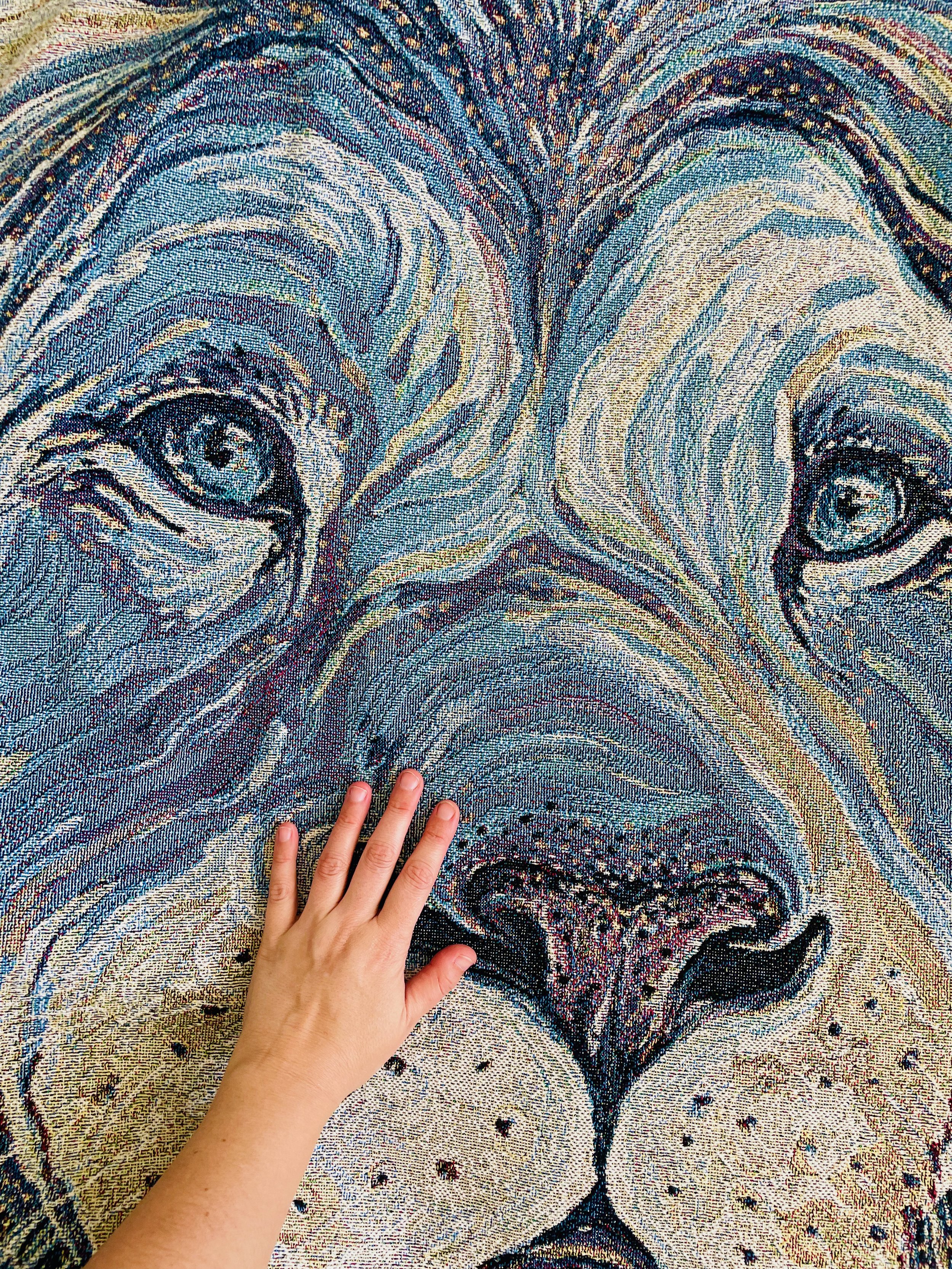 a close up of the white lion woven blanket with my white hand placed on it