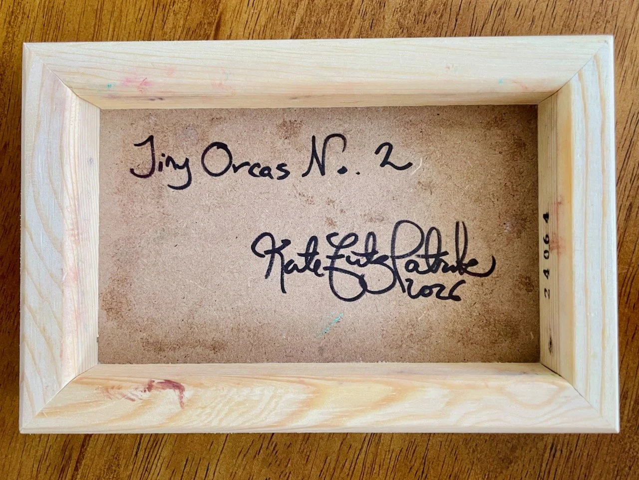 backside of the canvas with handwriting that reads tiny orcas no 2 kate fitzpatrick 2026