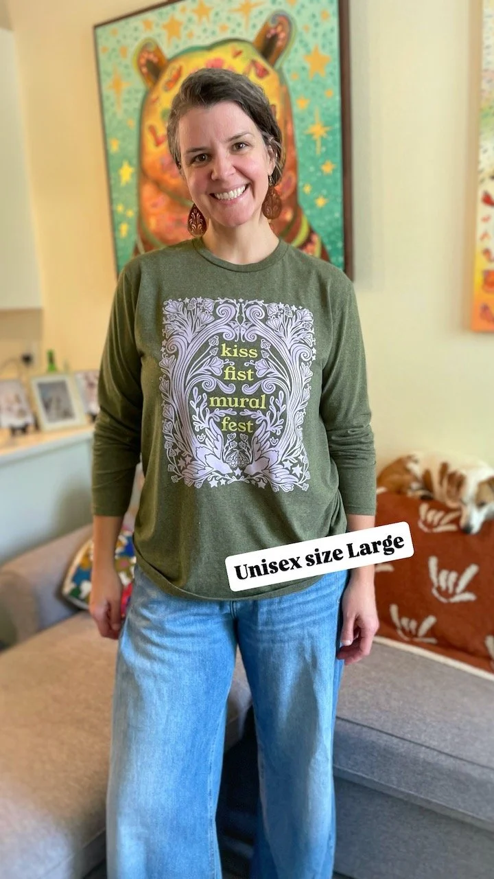 kate, a white woman with brown hair, smiles to camera showing the front of the shirt