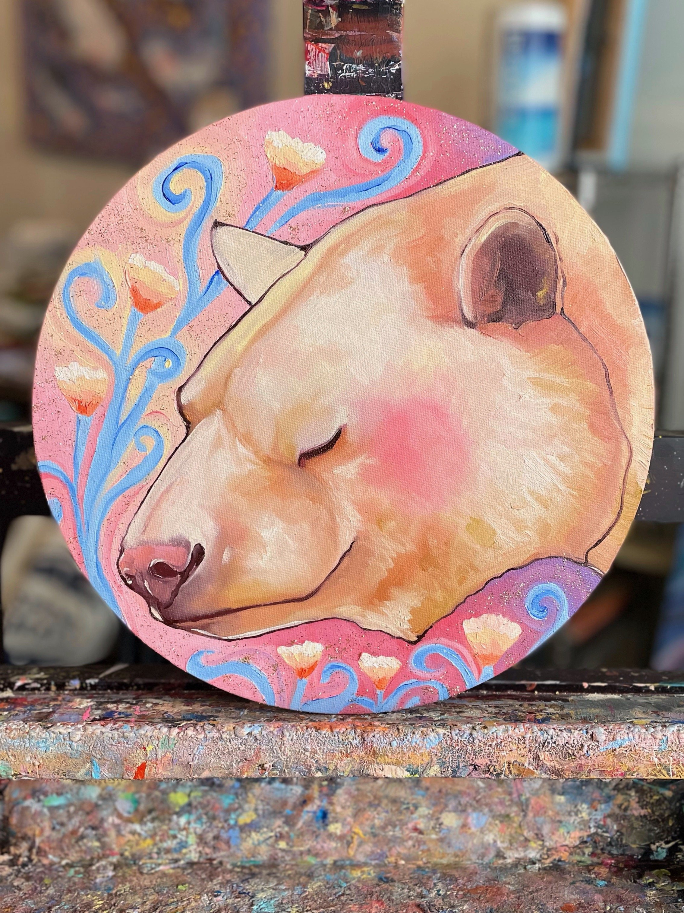A round painting of a kermode bear with its eyes closed