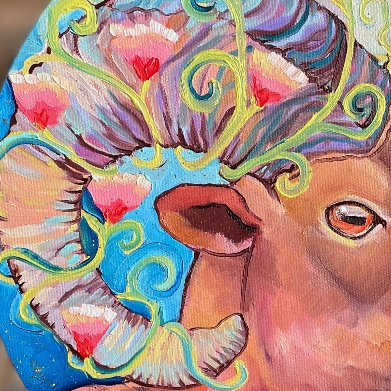 A round painting of a bighorn sheep with flowers around its horns