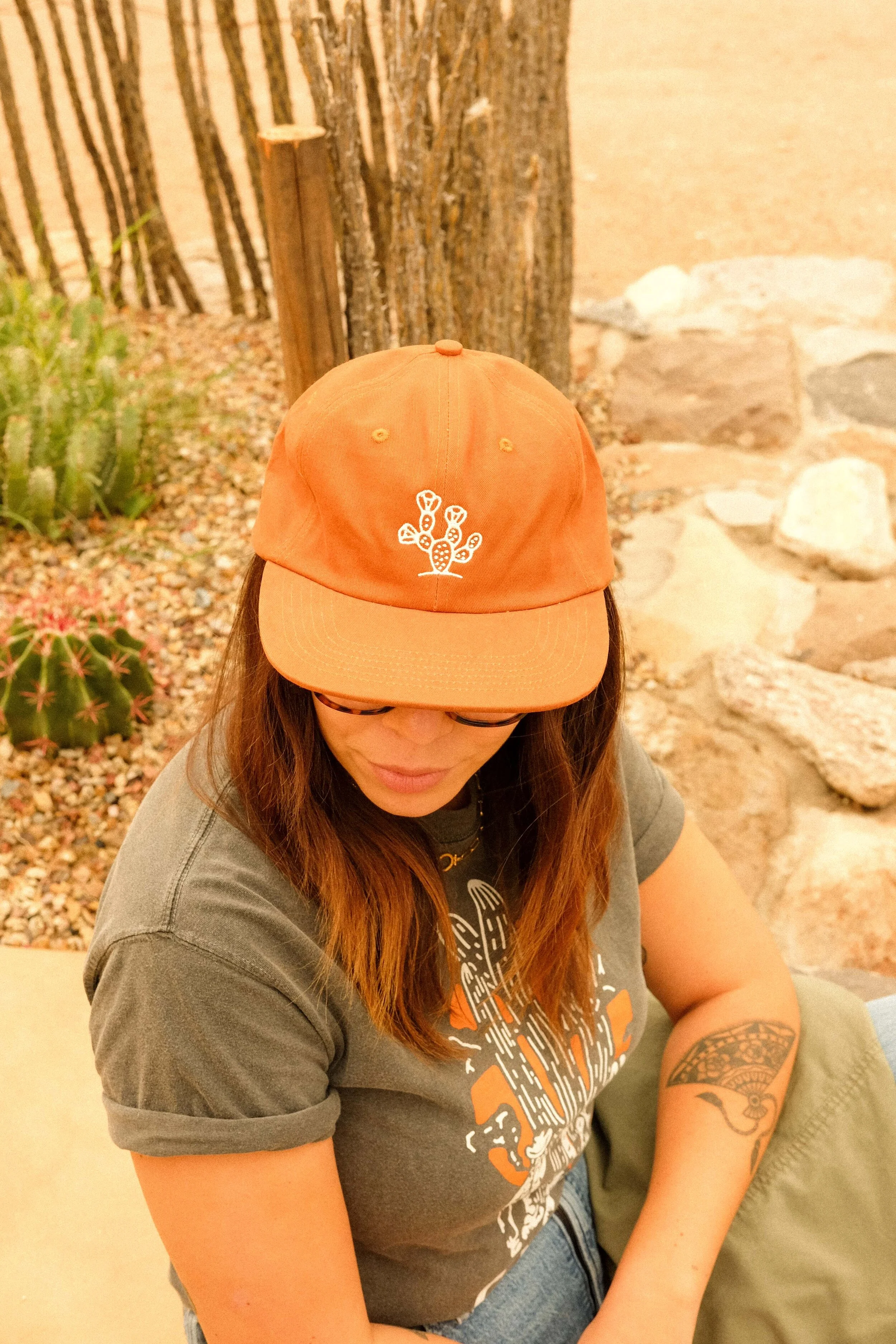 Woman wearing Cactus Country prickly pear hat in desert, showcasing hand-drawn design.