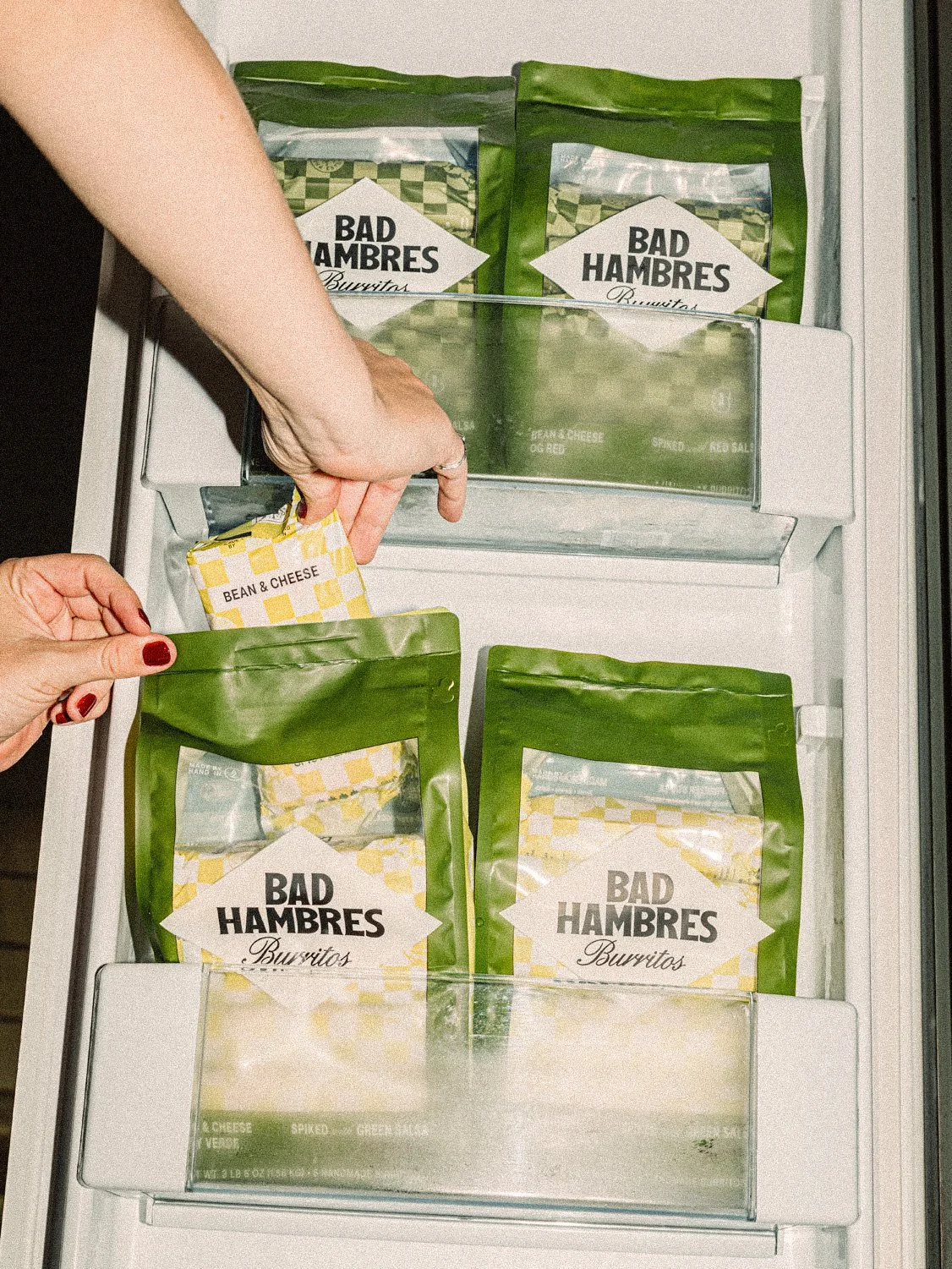 Bad Hambres 6-pack burrito bag designs for Verde and OG Red collections presented in freezer