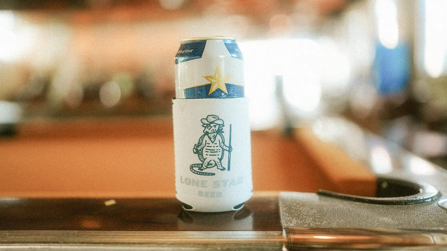 Lone Star Beer can with custom koozie design on dive bar pool table