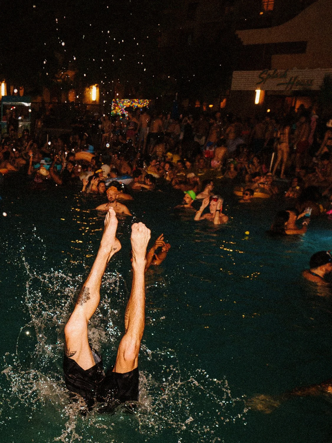 Night party with diver splashing in pool at Splash House music festival.