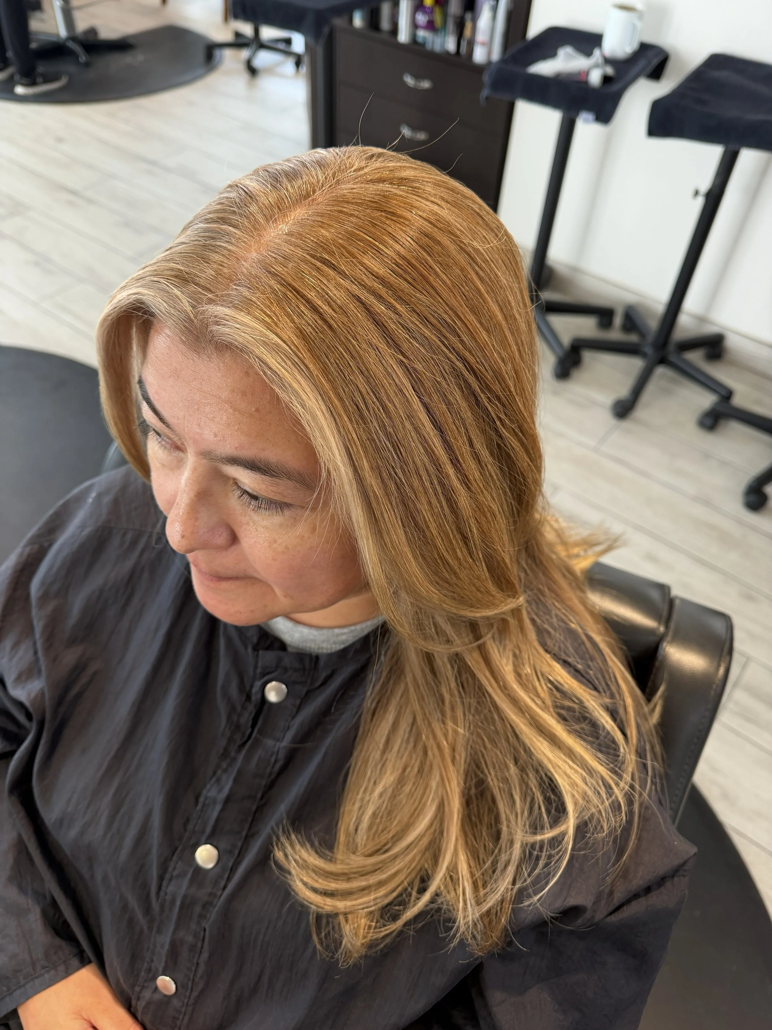 Glossy warm hair color with dimensional tones at Salon Sonik
