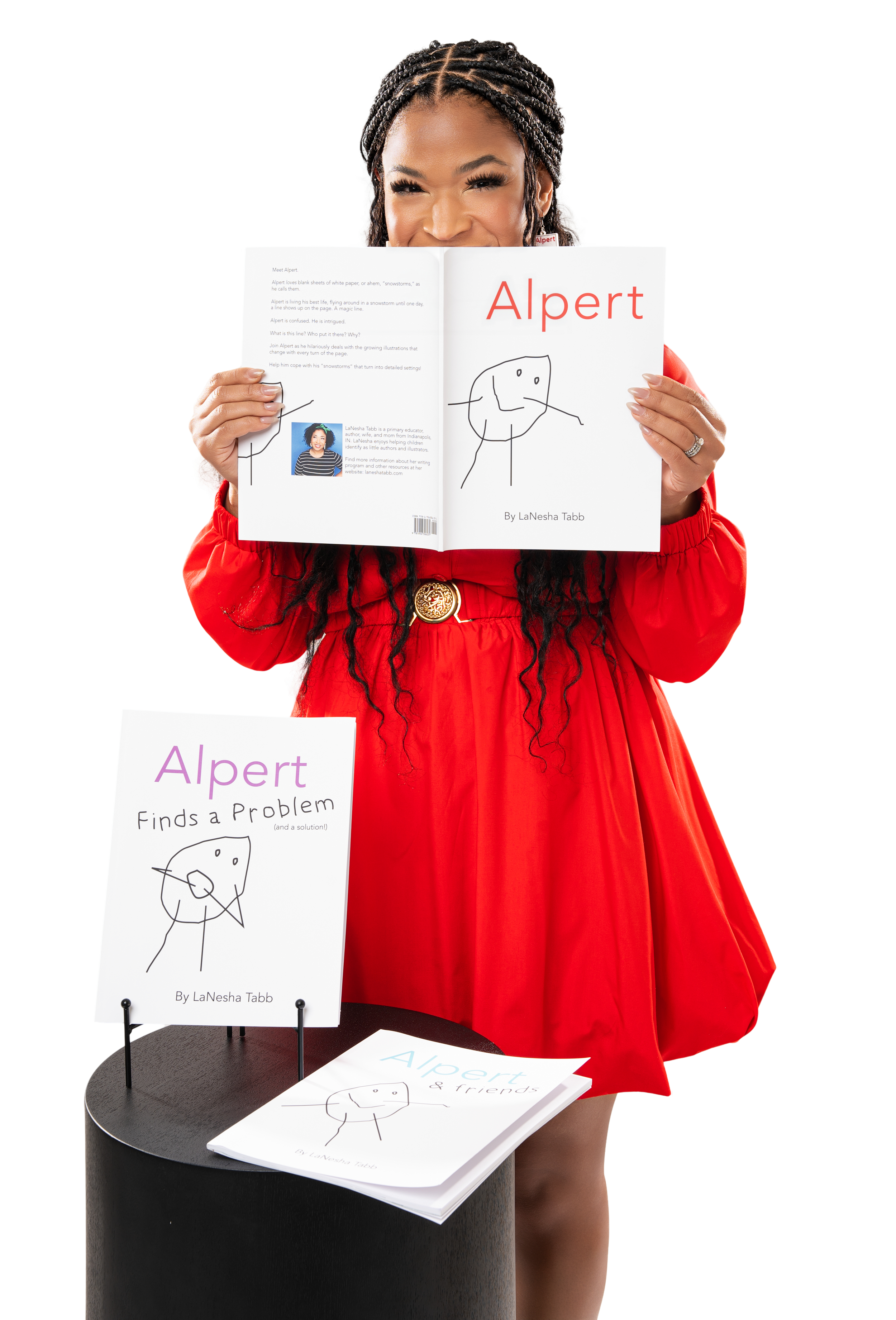 Person in red dress holding a book titled 'Alpert' with two other books displayed on a black cylindrical stand. The books feature simple line art on white covers.