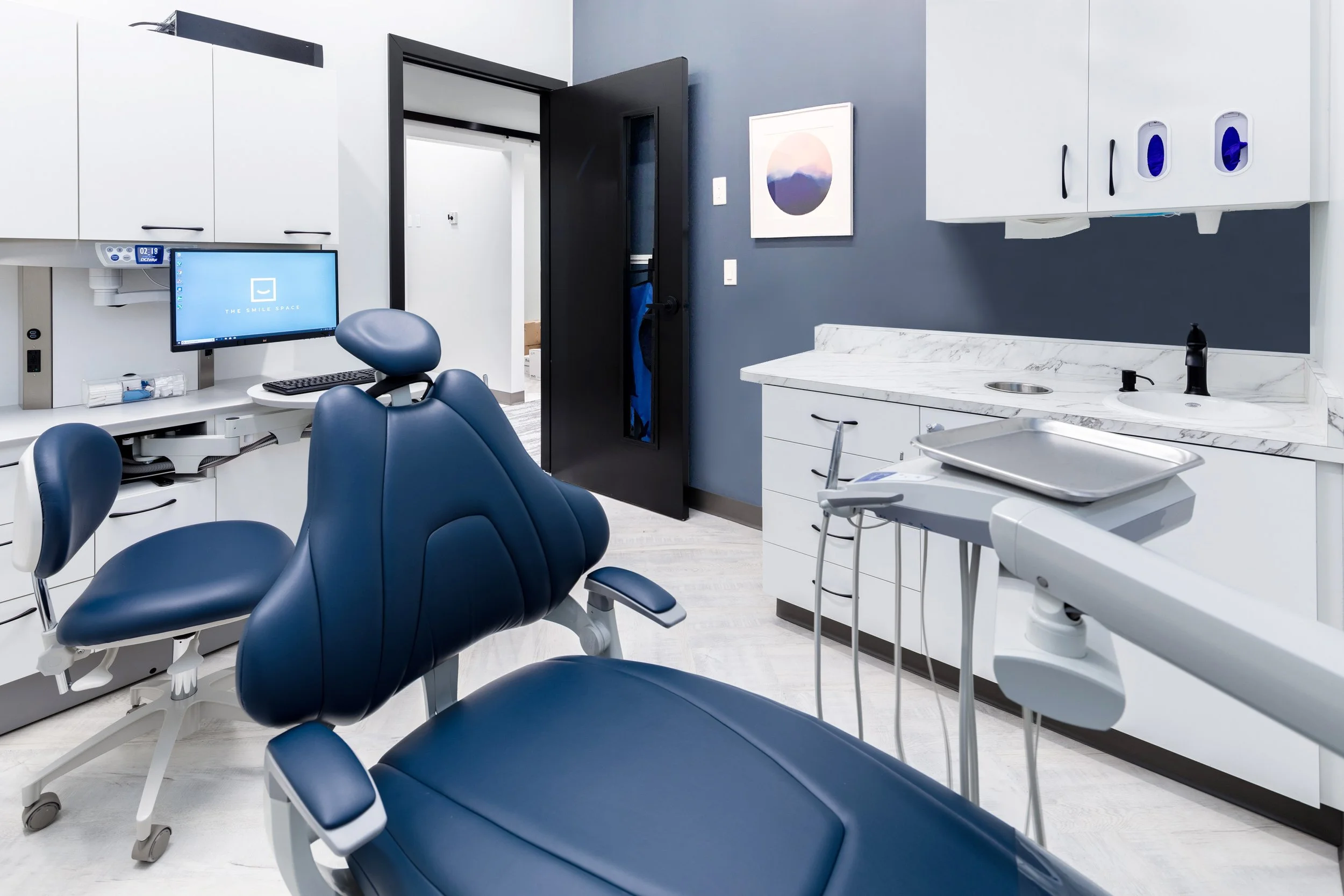 Private dental treatment room at The Smile Space featuring a comfortable patient chair, digital monitor, overhead light, and built-in cabinetry.