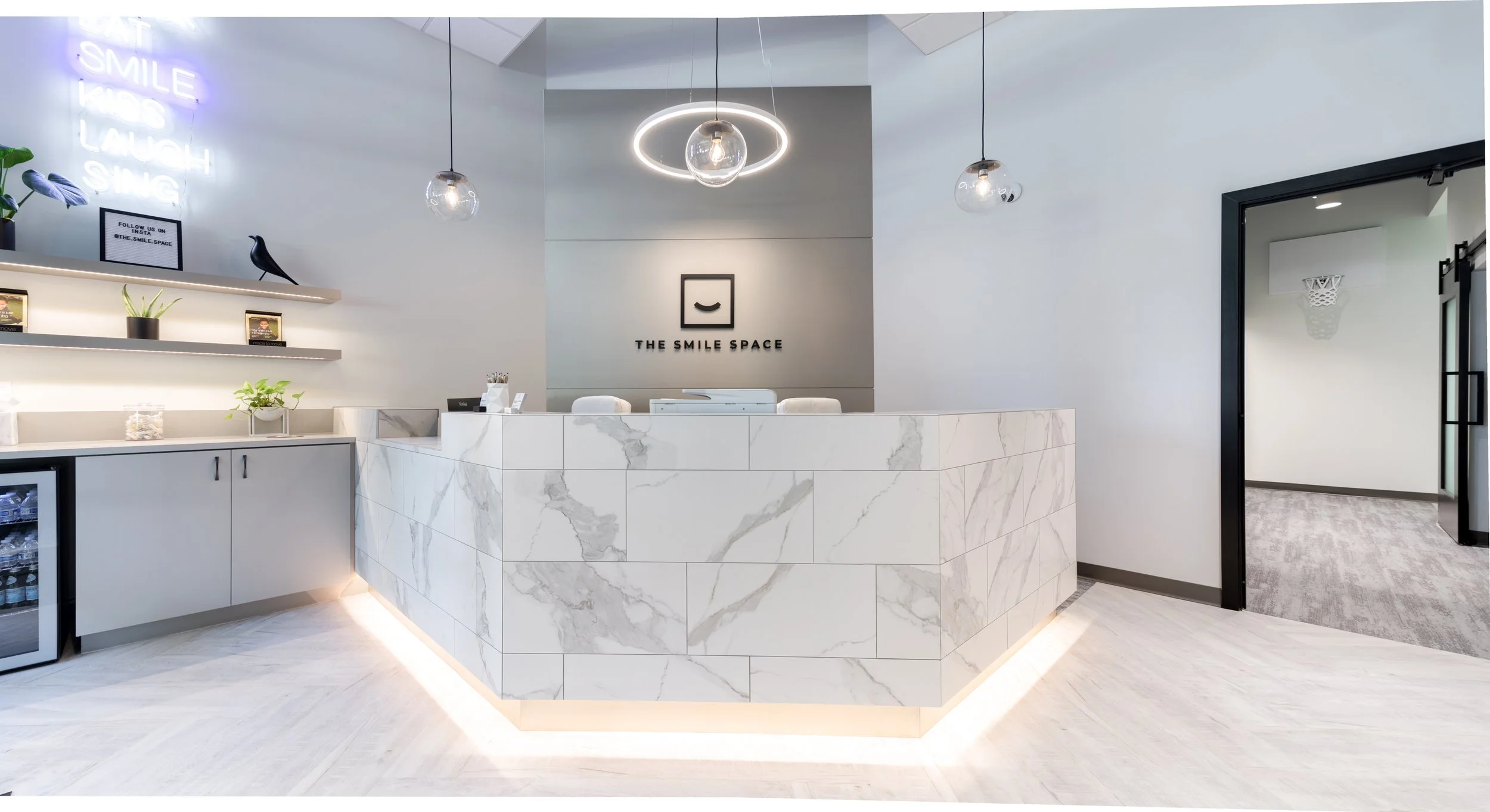 Modern reception desk at The Smile Space featuring a marble reception counter, contemporary lighting, and a bright, welcoming patient check-in area.