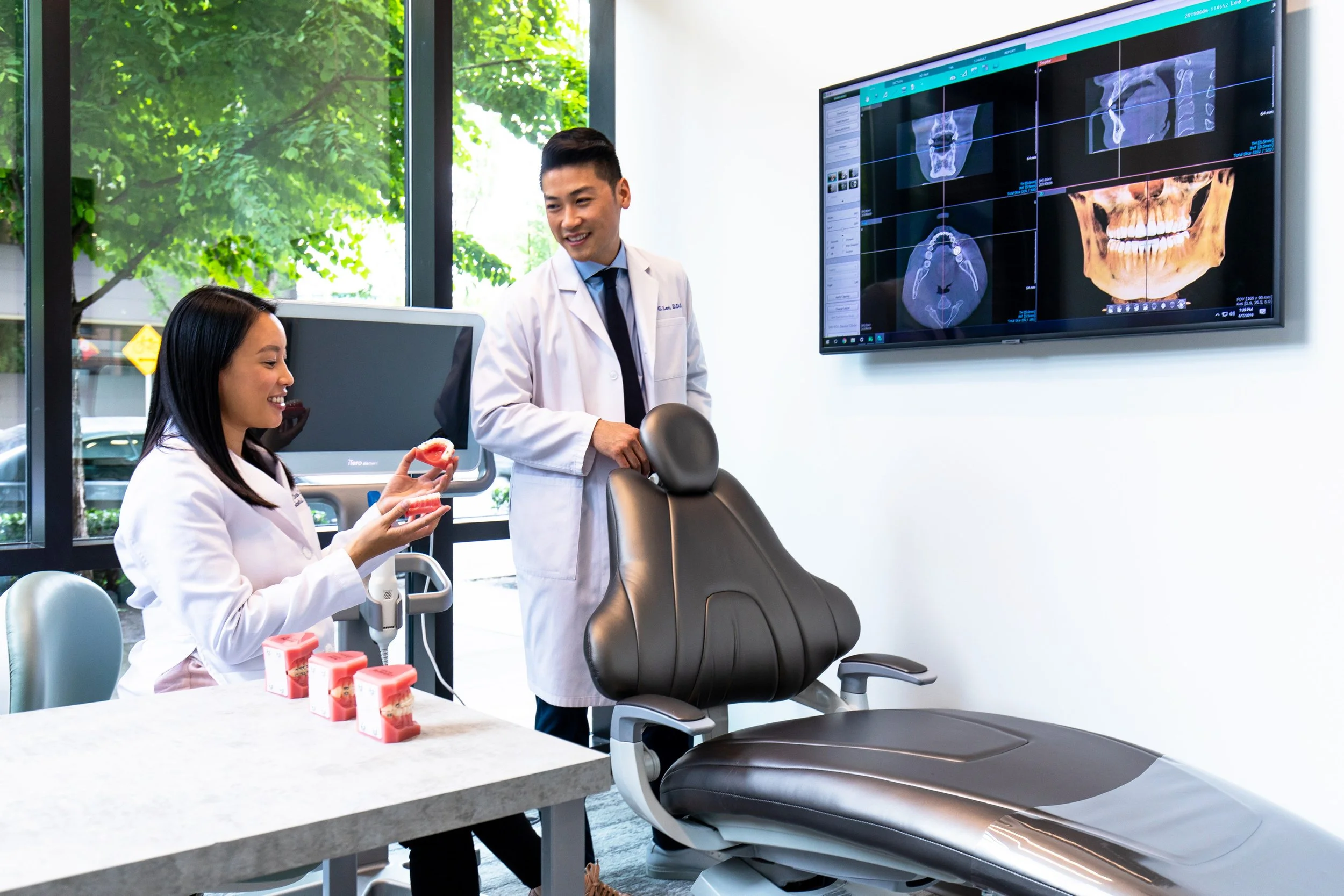 Dr. Christina Lee and Dr. Daniel Lee reviewing x-rays and dental models while collaboratively planning personalized dental and orthodontic treatment.