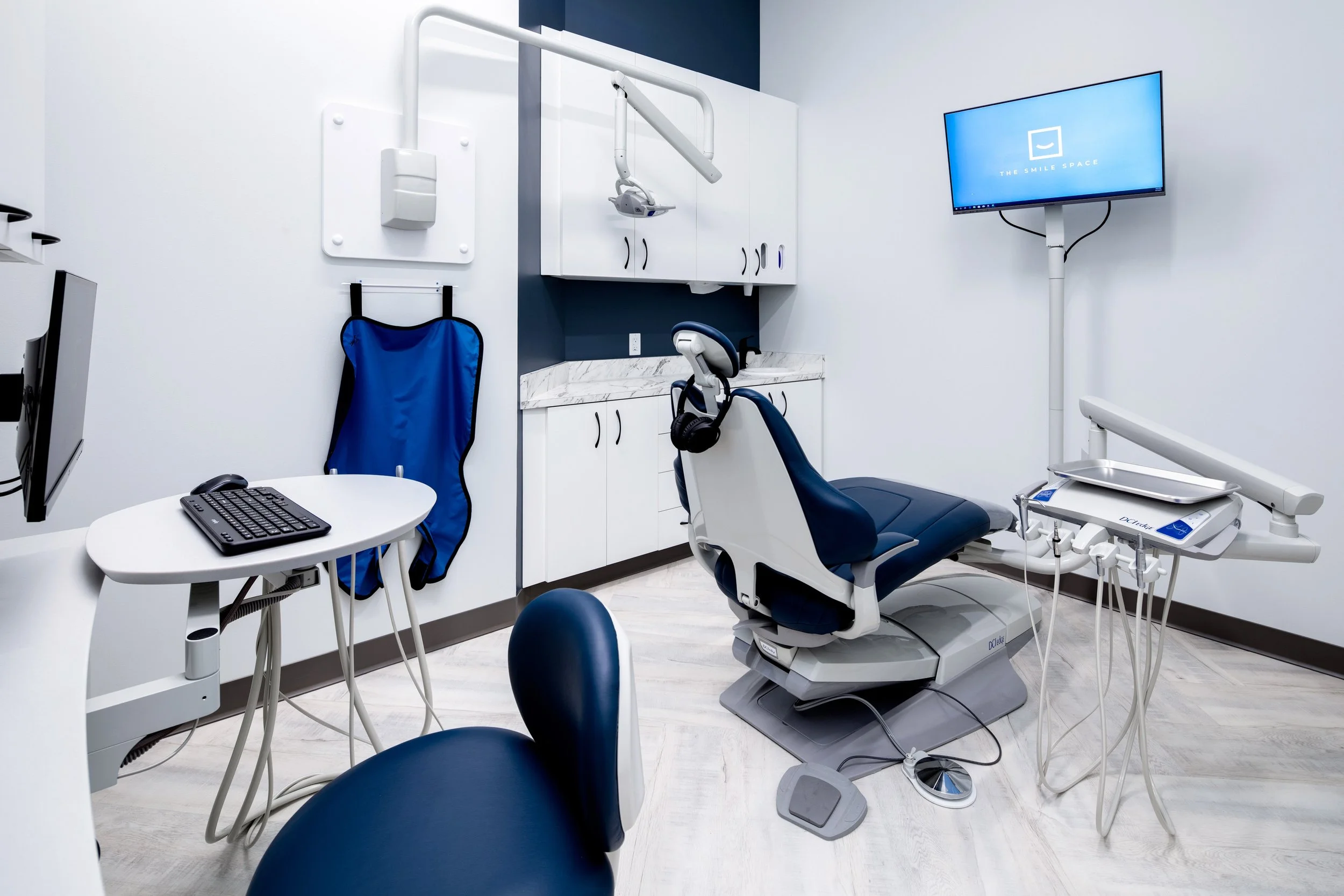 Private dental treatment room at The Smile Space featuring a modern patient chair, digital monitor, overhead light, and built-in cabinetry.