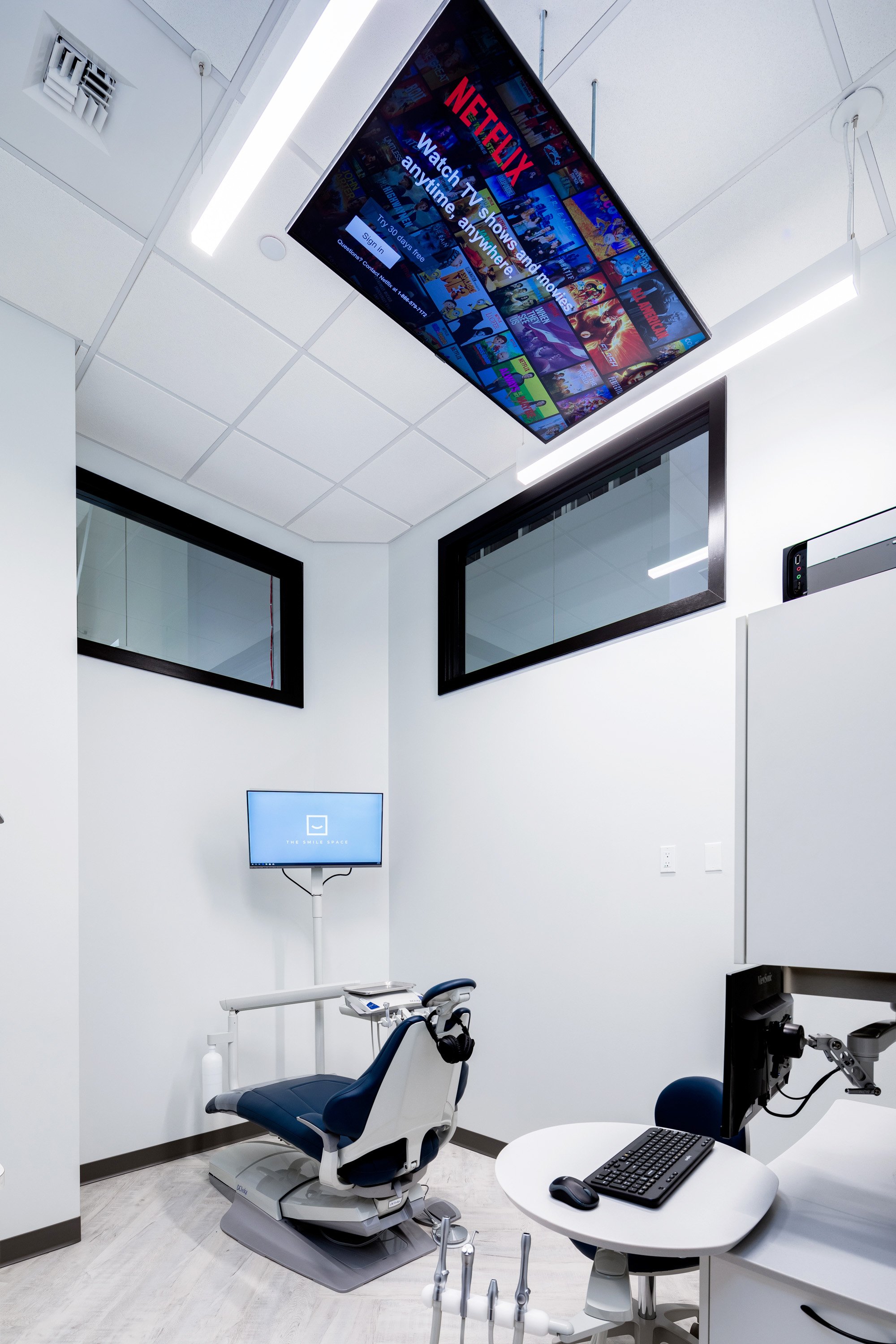 Private dental treatment room at The Smile Space featuring a ceiling-mounted TV, comfortable patient chair, and modern treatment equipment.