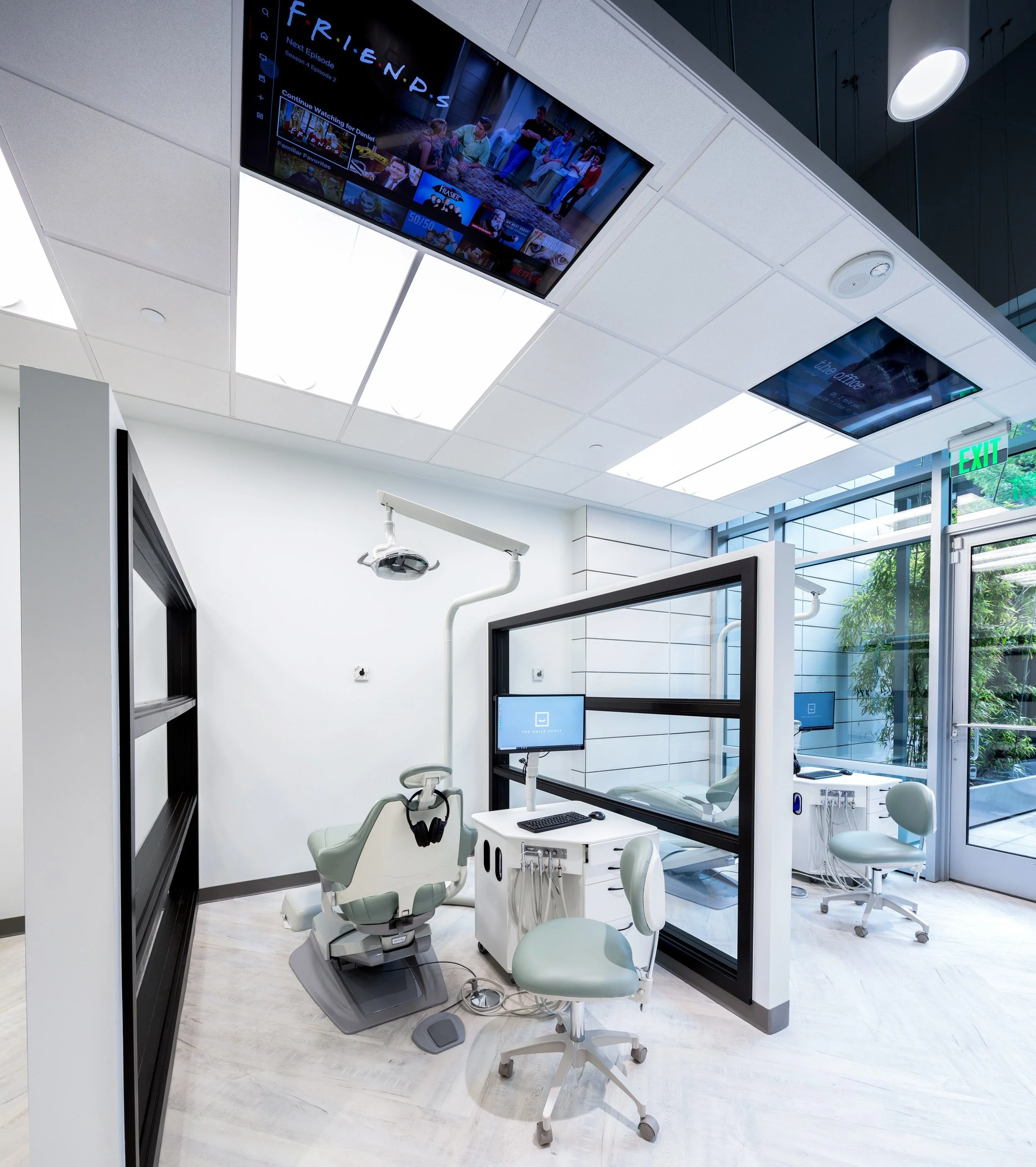 Bright, modern orthodontic treatment area at The Smile Space featuring open bay chairs and ceiling-mounted TVs for patient comfort.