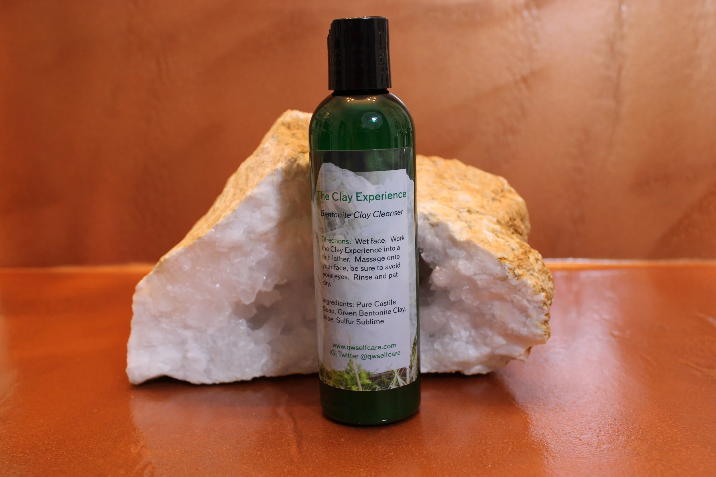 QW Self Care The Clay Experience product photo.  Copper background with large clear quartz crystal