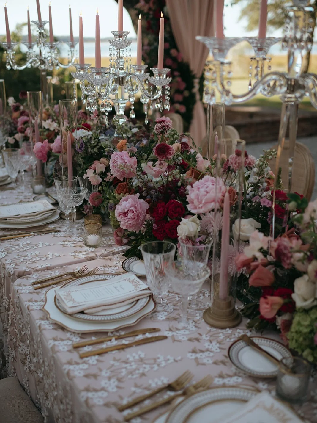 For Courtney and Patrick, their reception design felt less like an event and more like stepping into a painting at golden hour. Soft light poured through their lush canopy of florals, while candlelight, atop layered blush and cream linens, flickered 