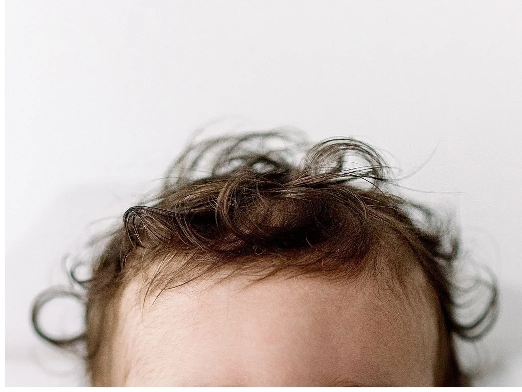 Detail close up of a baby's curly brown hair on a white background during a baby session in Oshawa