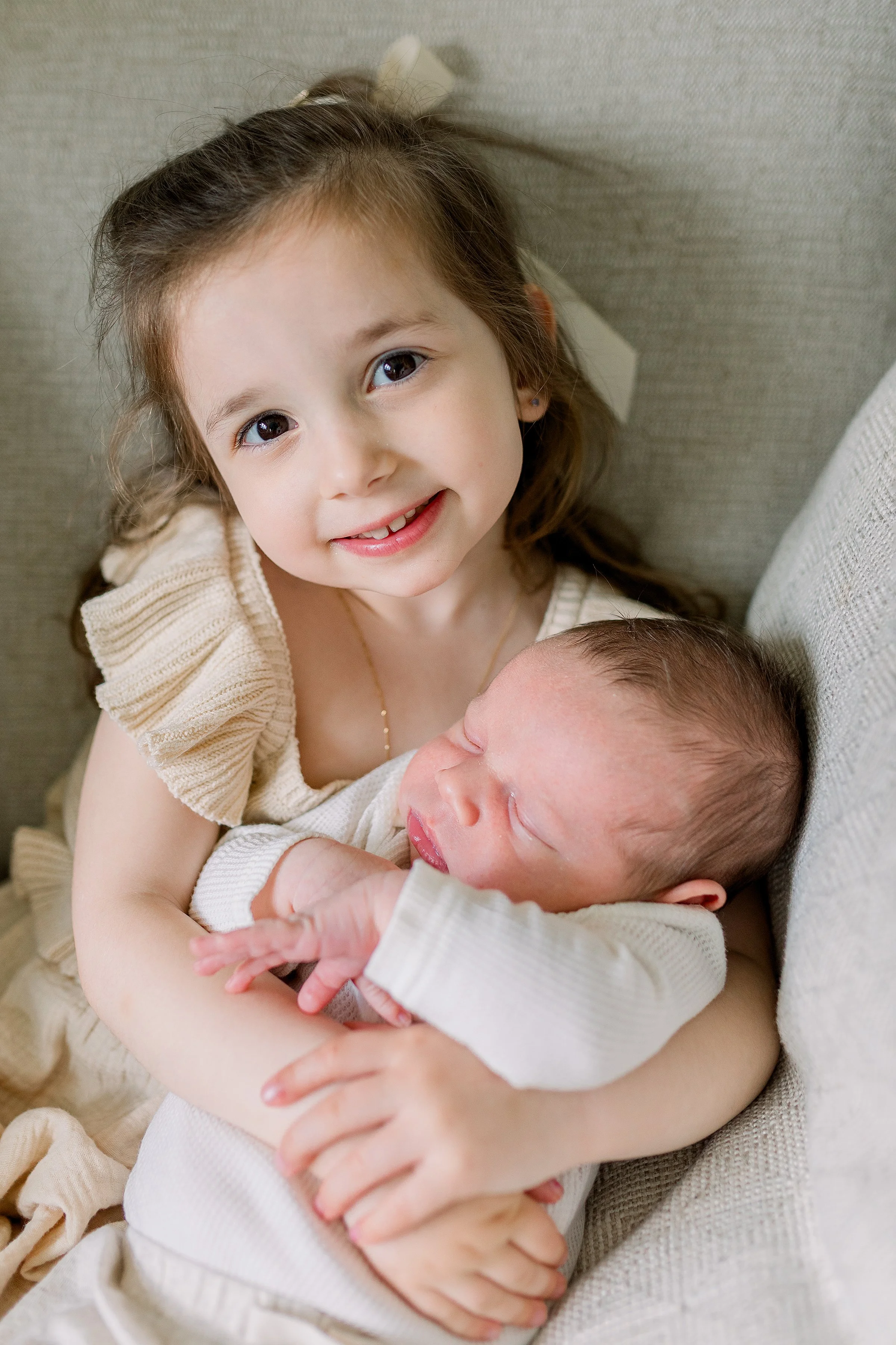 Big sister smiling holding newborn baby