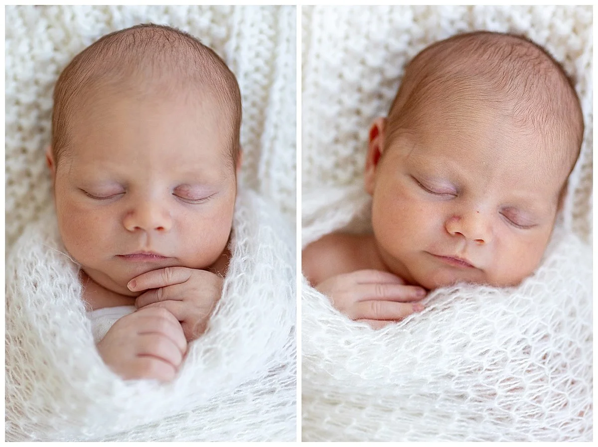 Close-up of a sleeping baby wrapped in a white knit blanket, with eyes closed and hands folded near the chin.