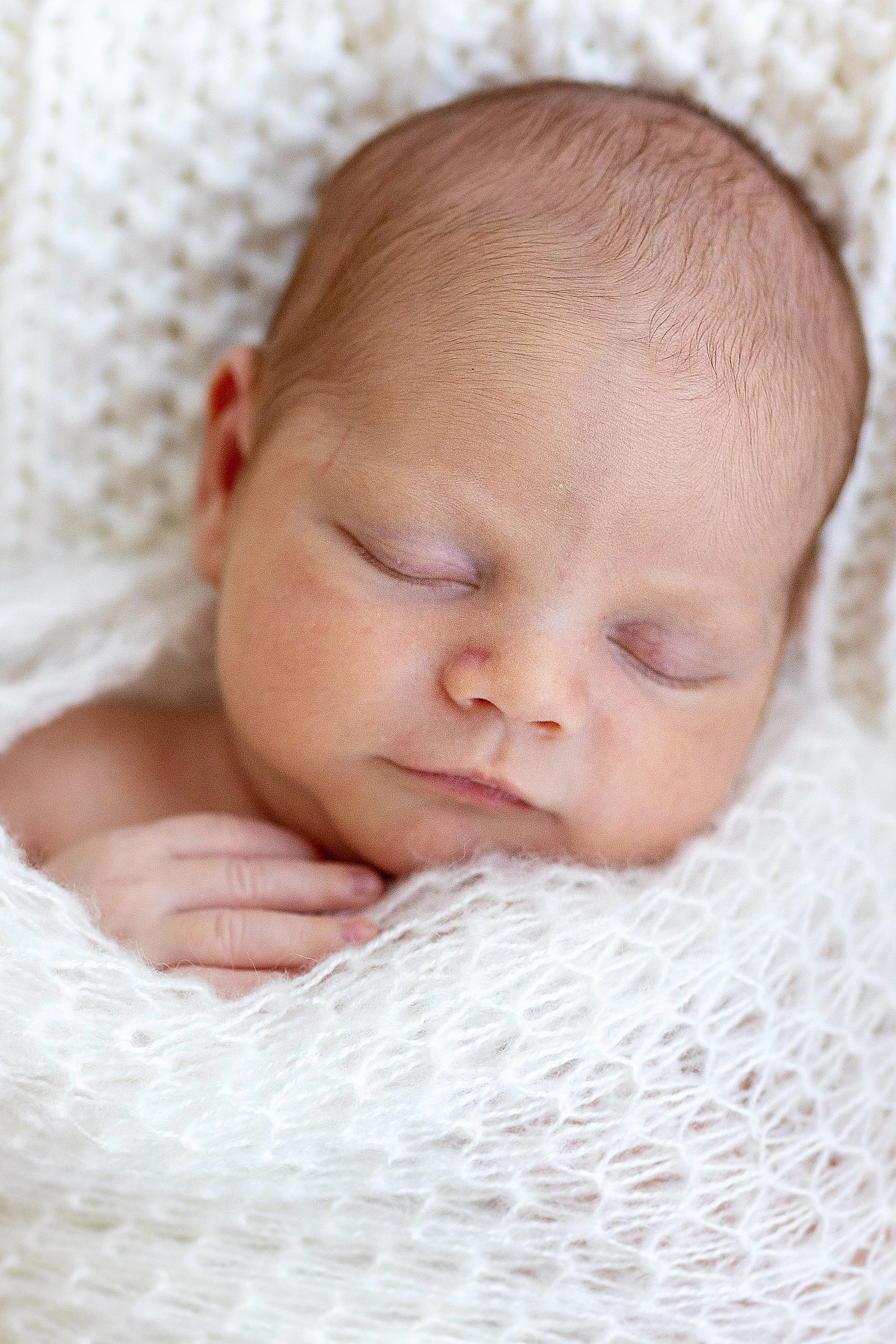 Sleeping baby wrapped in white during newborn session in Oshawa, Durham Region