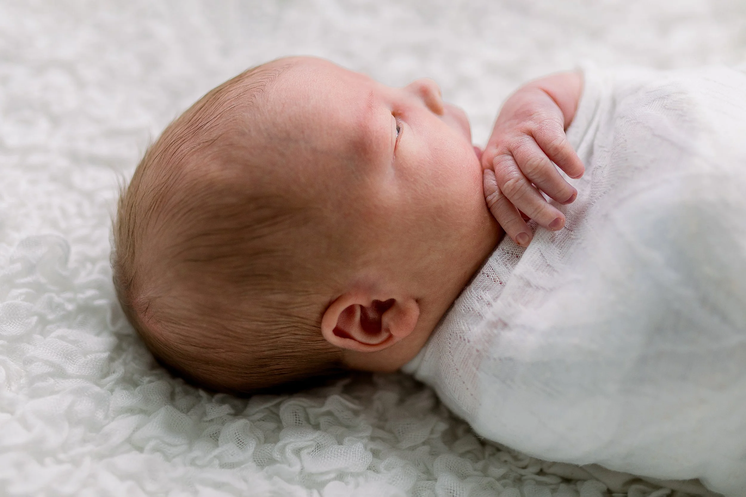 Newborn in white wrap awake in Oshawa baby studio