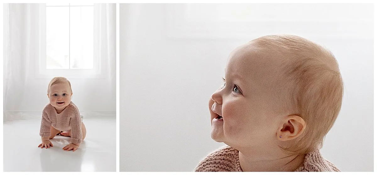 Cute chubby baby girl with red hair and a pink knit sweater crawling on white studio floor and a side profile of her face smiling during a baby session in Durham Region