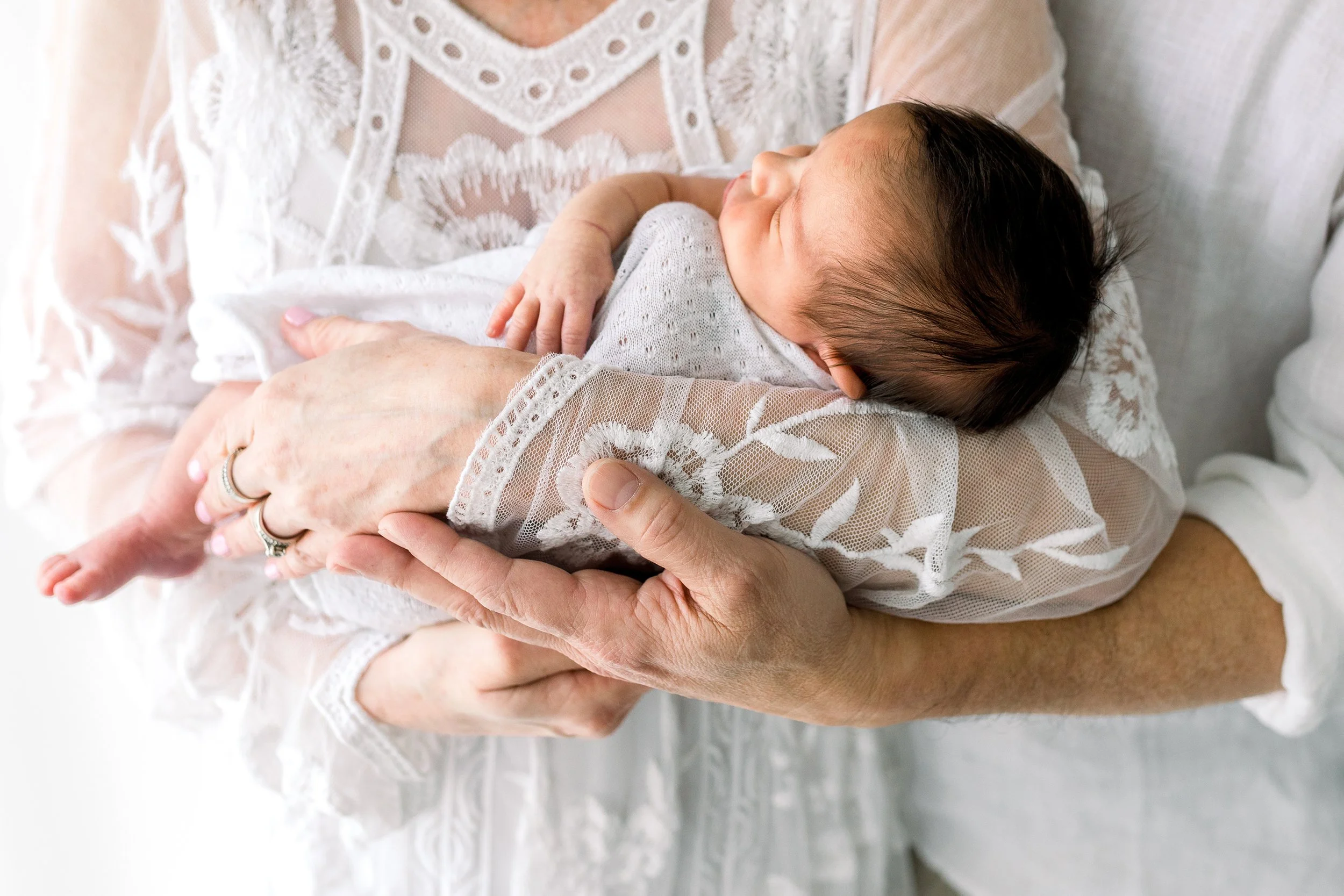 Parents holding sleeping baby during newborn studio session in Durham Region
