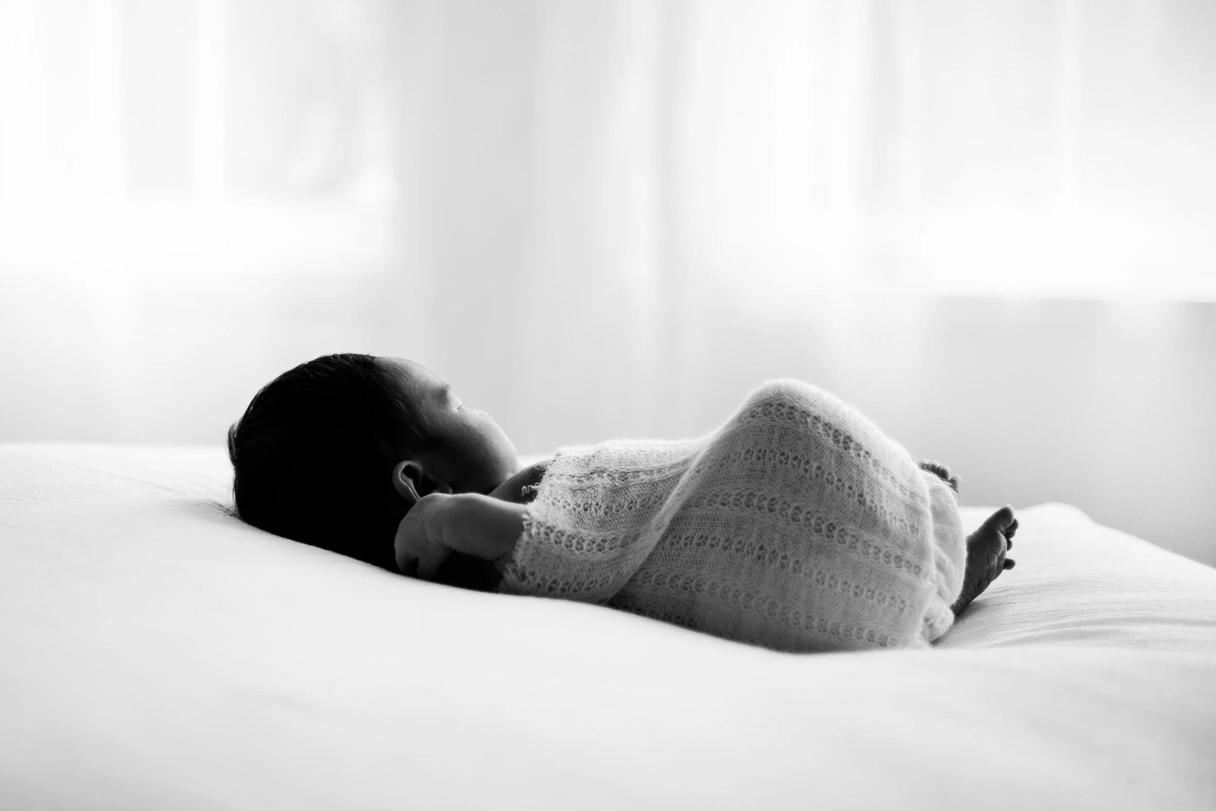 Sleeping newborn in black and white in front of window in Oshawa