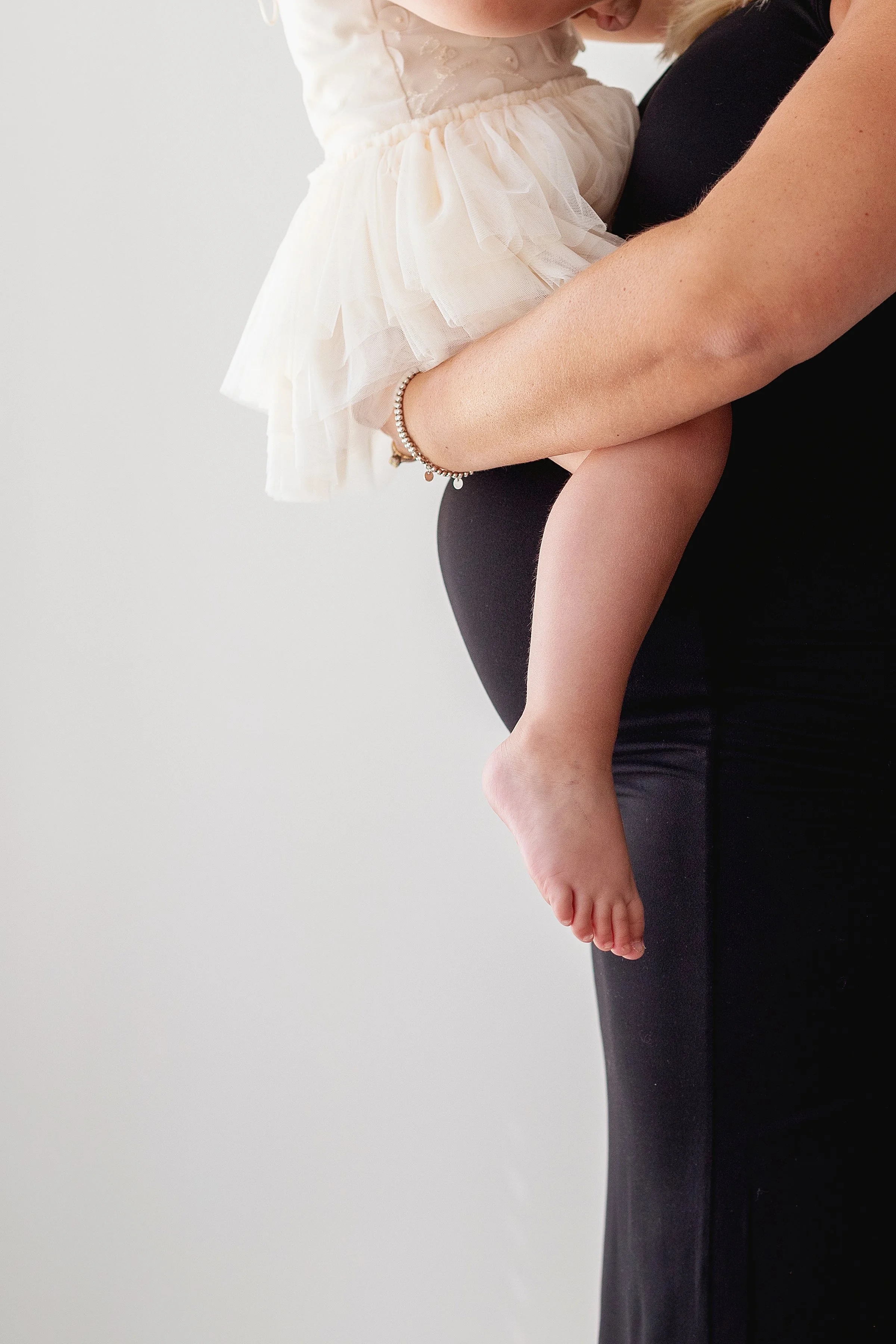 Mom to be holding toddler on her belly in black dress