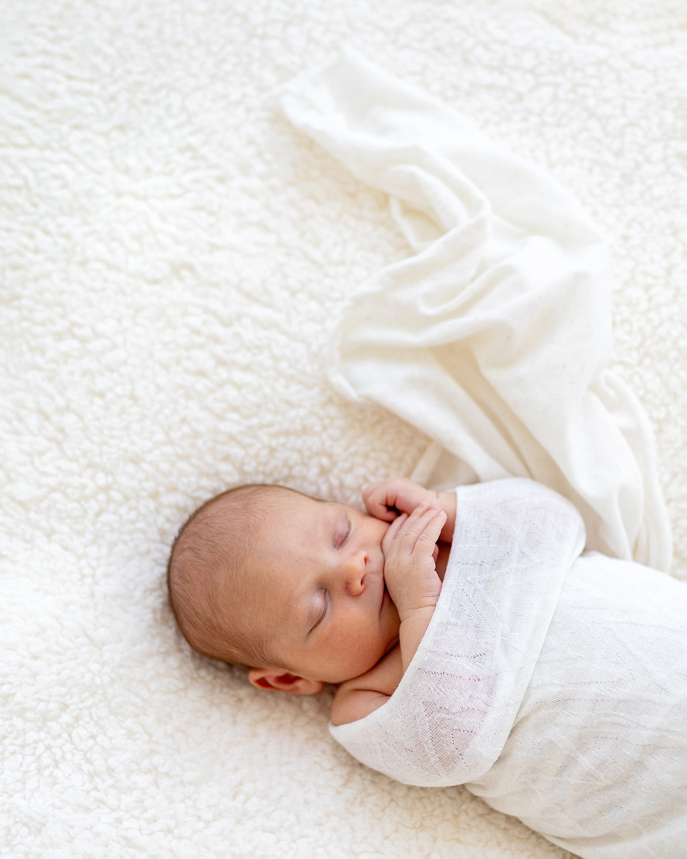 Newborn wrapped in white linen sleeping during newborn baby studio session Durham Region