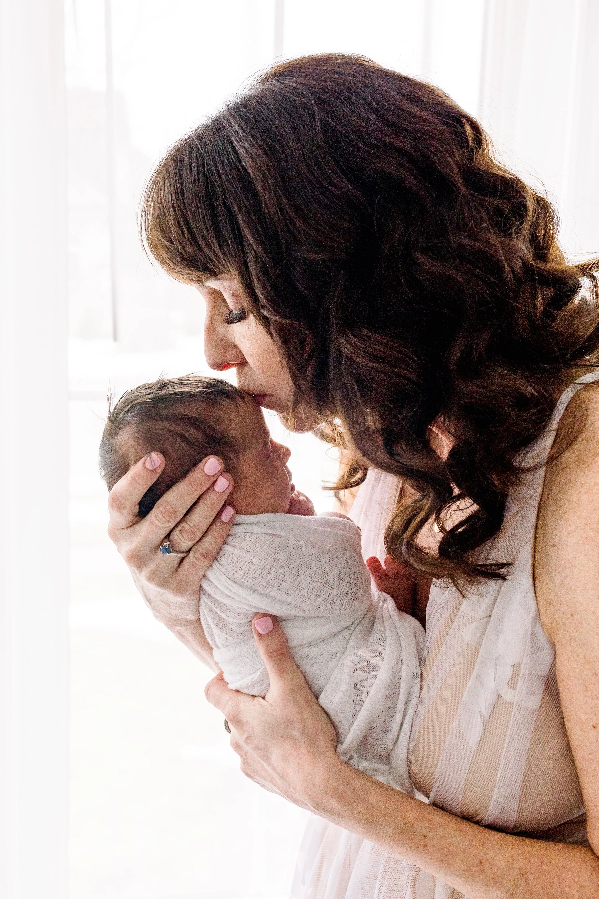 Mom kissing newborn's head in her newborn studio session in Oshawa