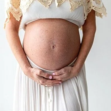 Pregnant mom in cream boho outfit holding belly