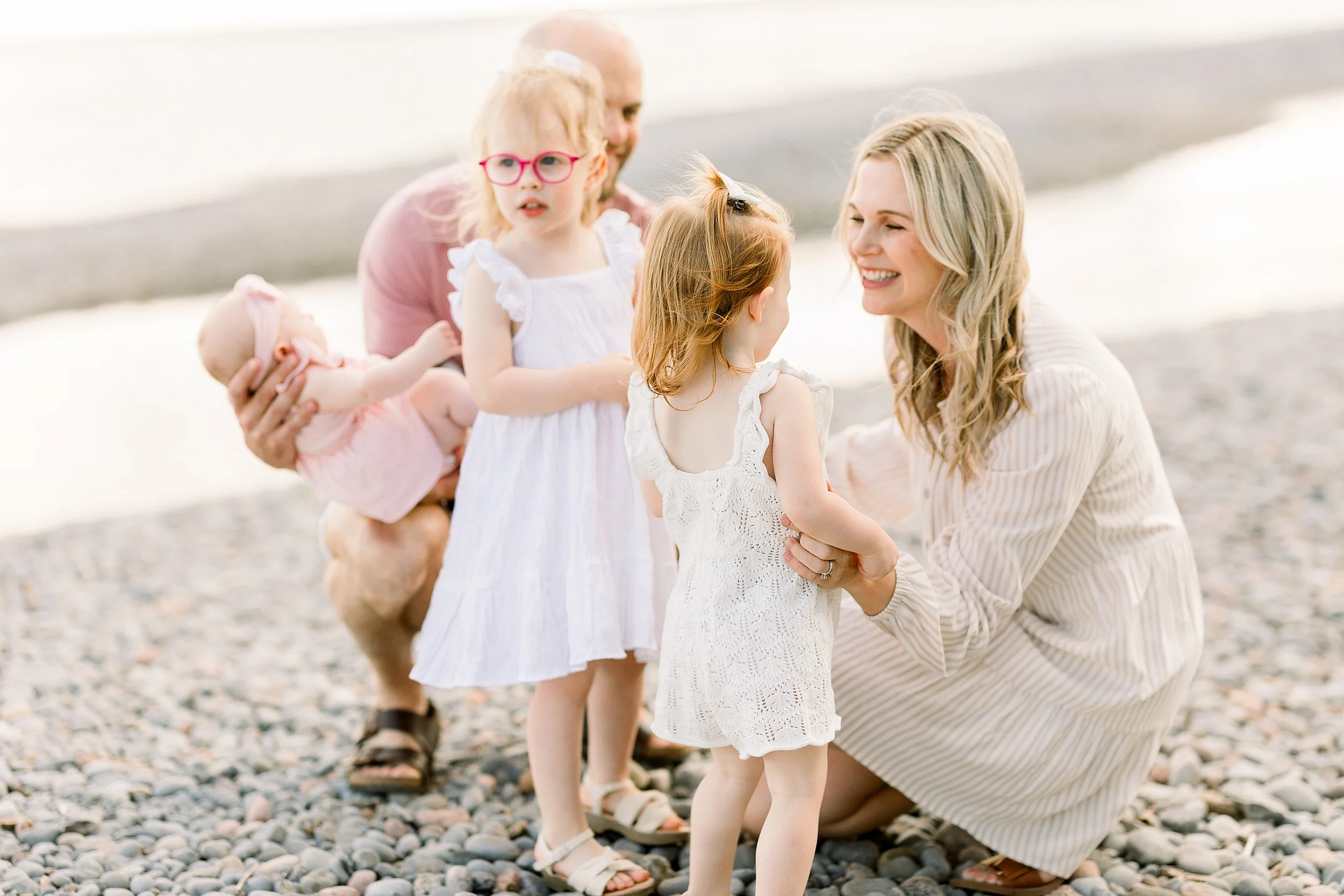 Family with 3 little girls on the beach having fun at golden hour