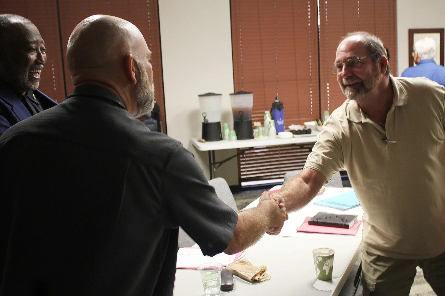 Mark George (right), a chaplain at the Caldwell County Jail in Lockhart, TX., shakes hands with VA clergy training instructor Larry Collins, while attendee Vernon Cooper looks on.