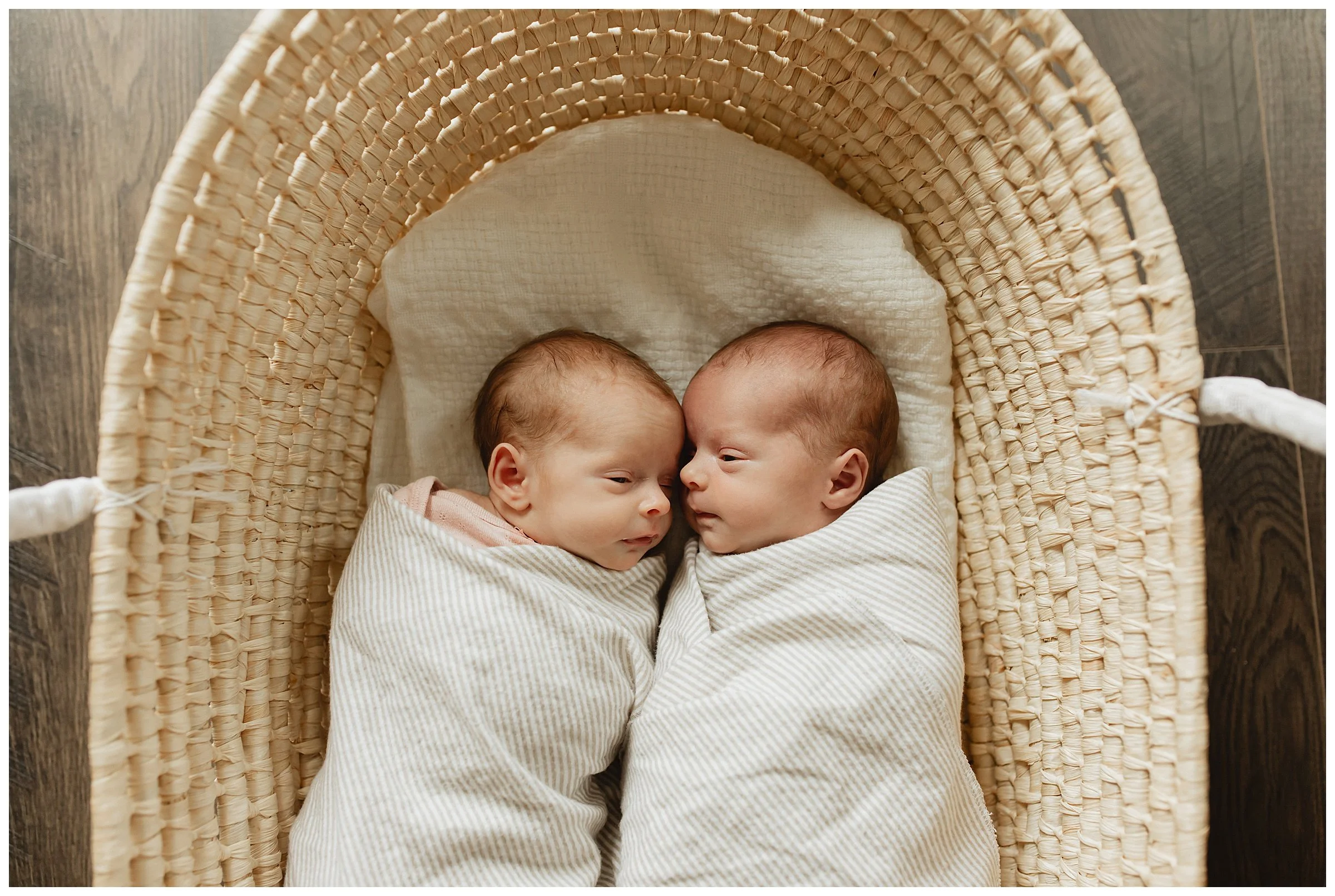   Close-up of newborn twins wrapped in neutral blankets during an in-home session  