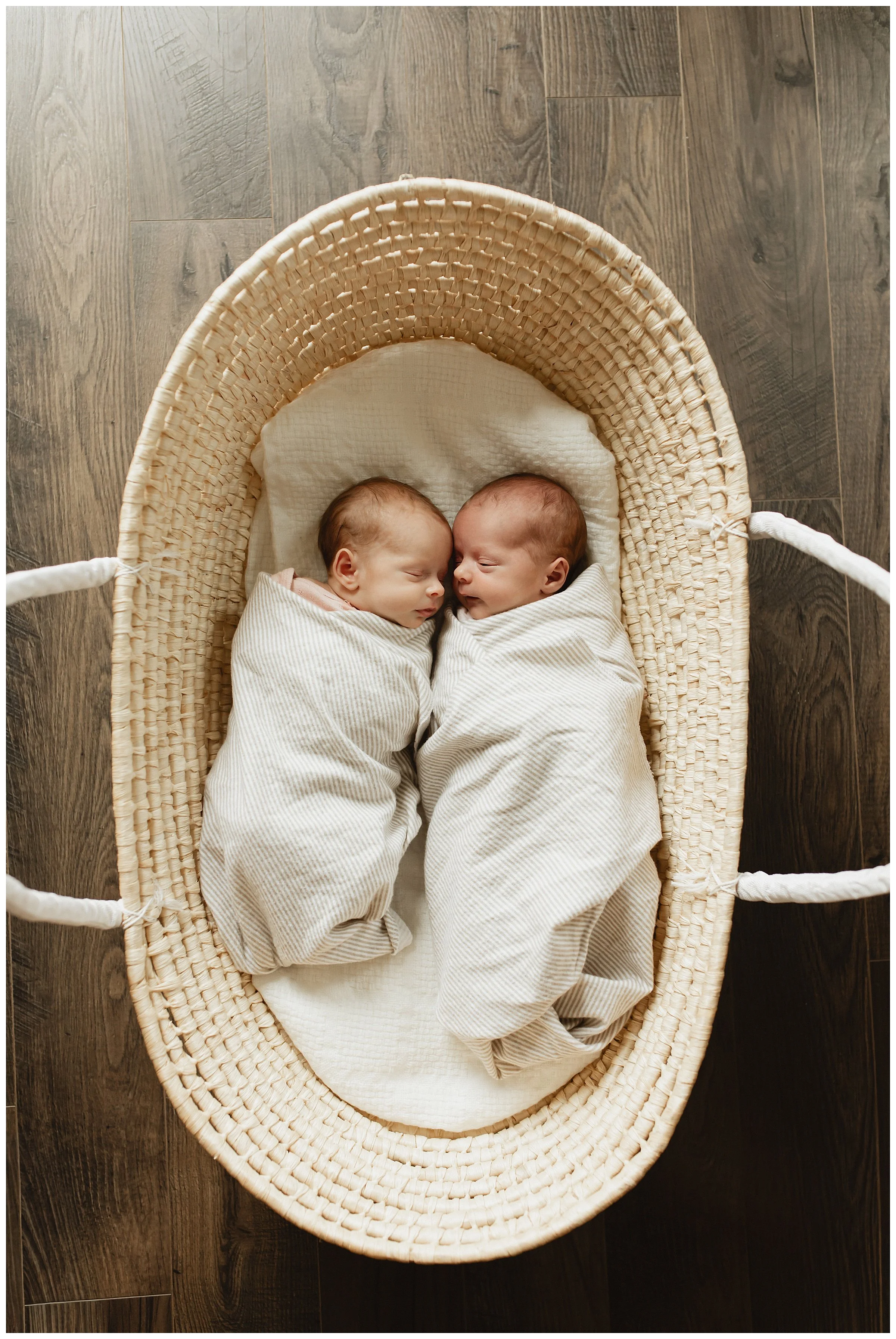   Close-up of newborn twins wrapped in neutral blankets during an in-home session  