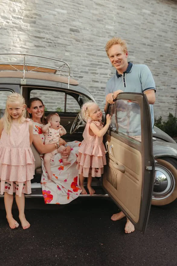 Family of five sit in and around classic volkswagon beetle