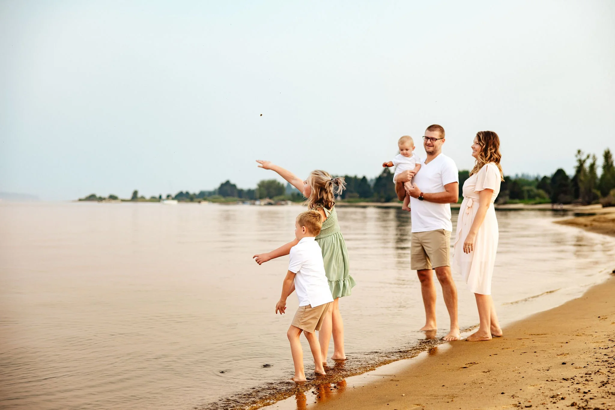 family of five throws rocks into the lake