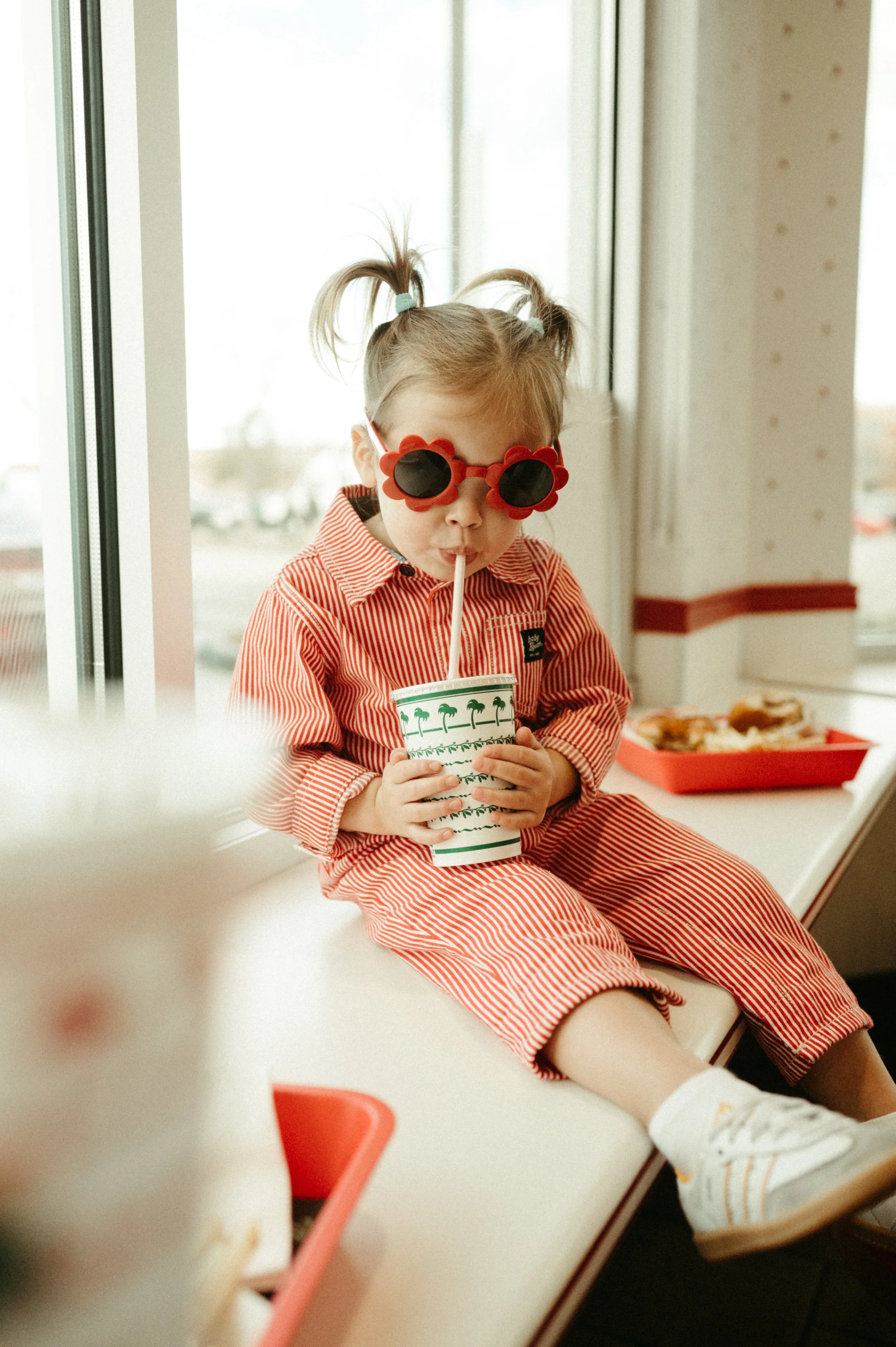 Little girl holding her drink, wearing flower sunglasses at in-n-out burger