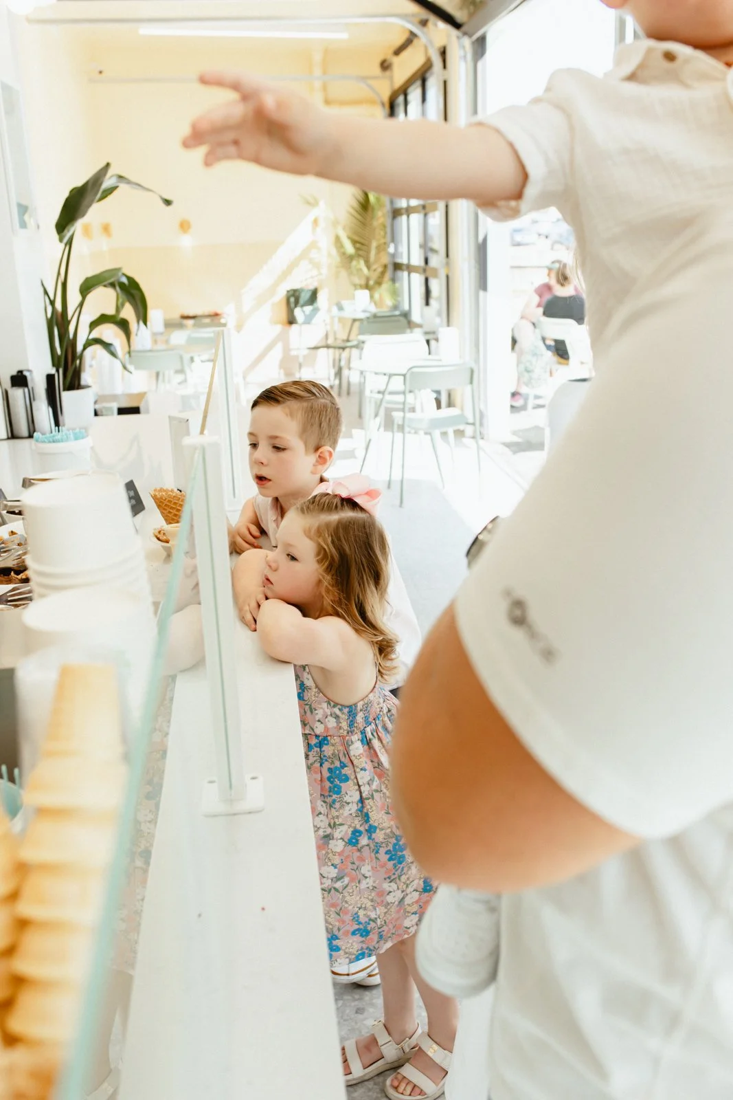Brother and sister peeking over ice cream counter