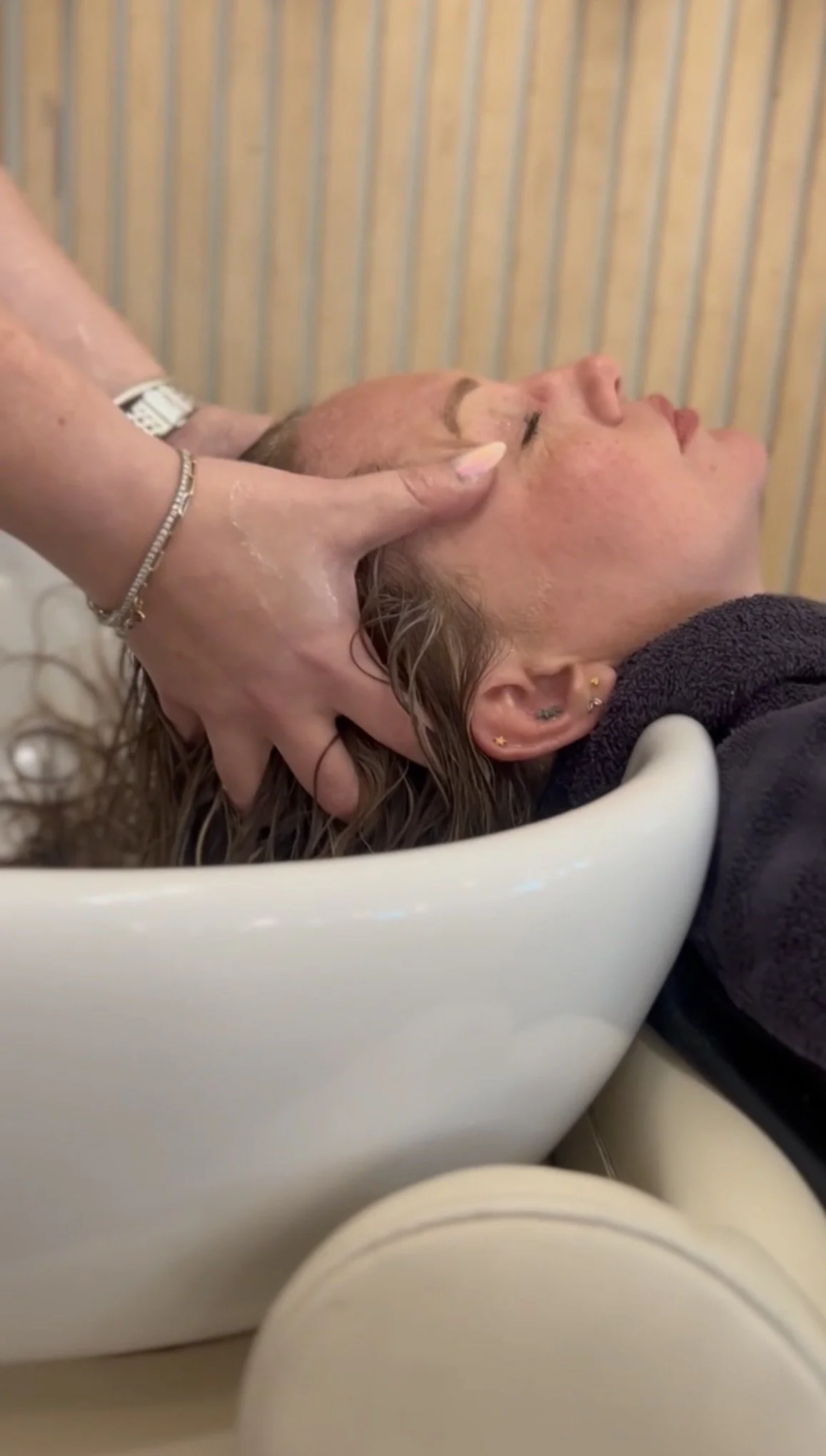 Stylist toning color at the shampoo bowl during a color appointment at Alchemy Park Style Bar