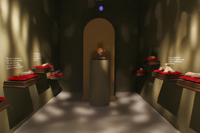 La Capilla de Los Palos , 2004. Slip-cast ceramic log forms, with oxides and gold luster, velvet pillows on baroque shelving, and cast resin head with programmed interior illumination. Dimensions variable.
