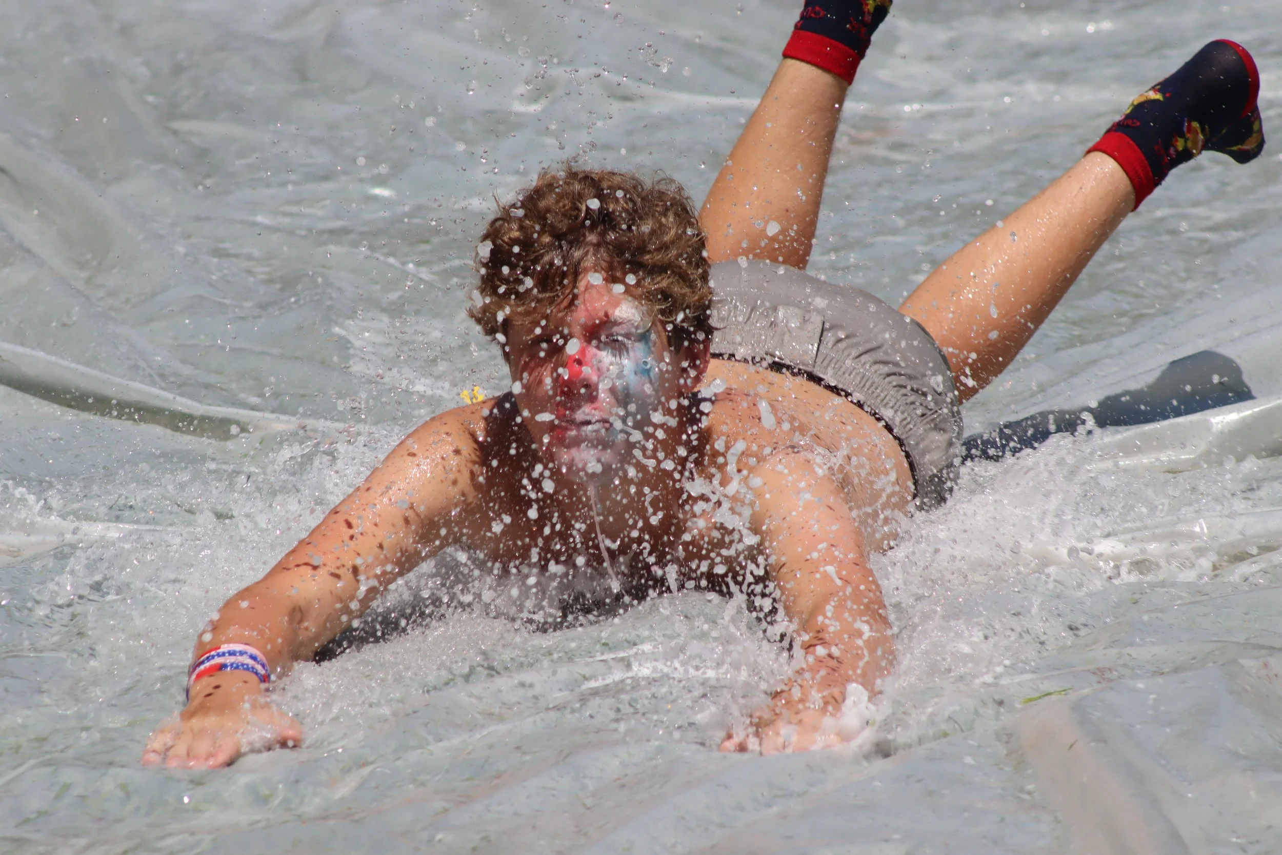 A slip and slide at camp with a boy on it .