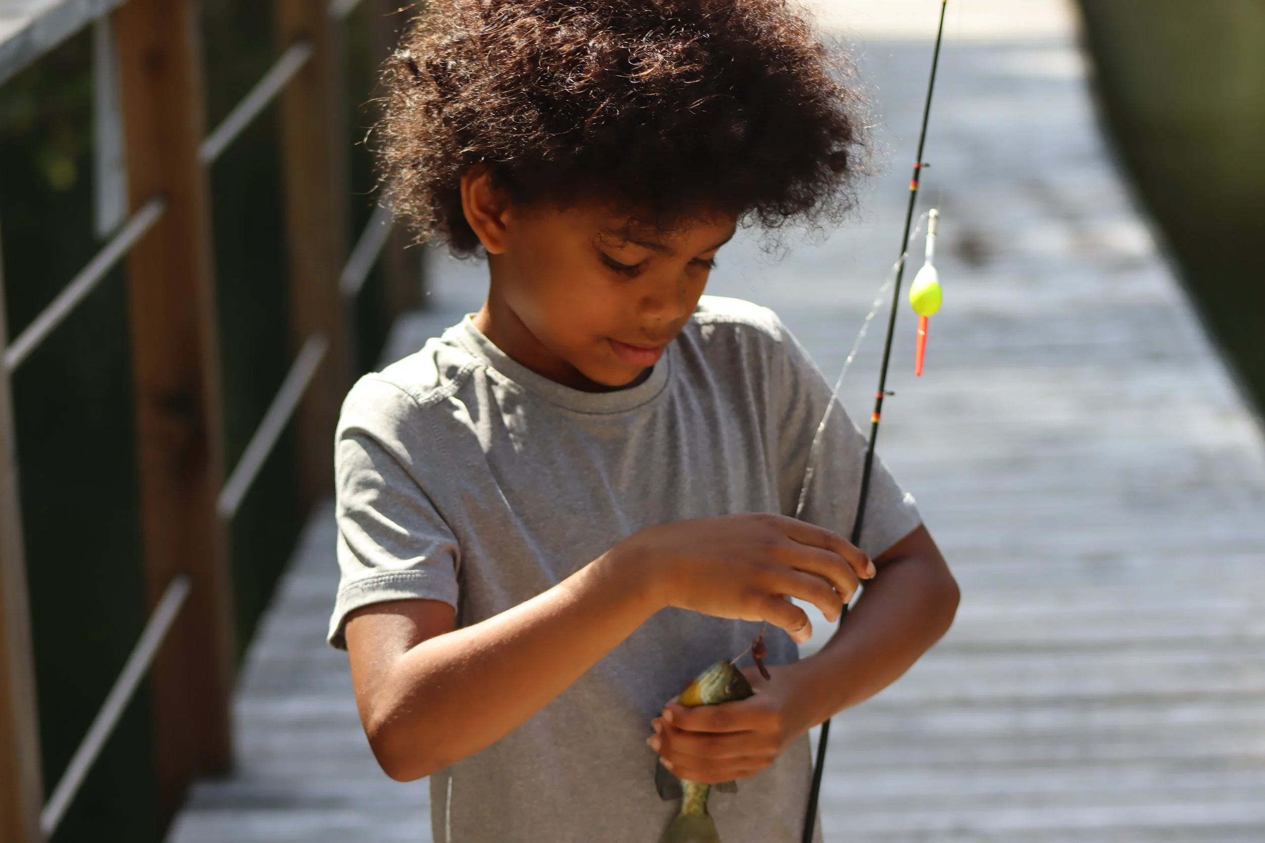 Camper prepares to remove a fish he caught from the hook at Camp Arrowhead.