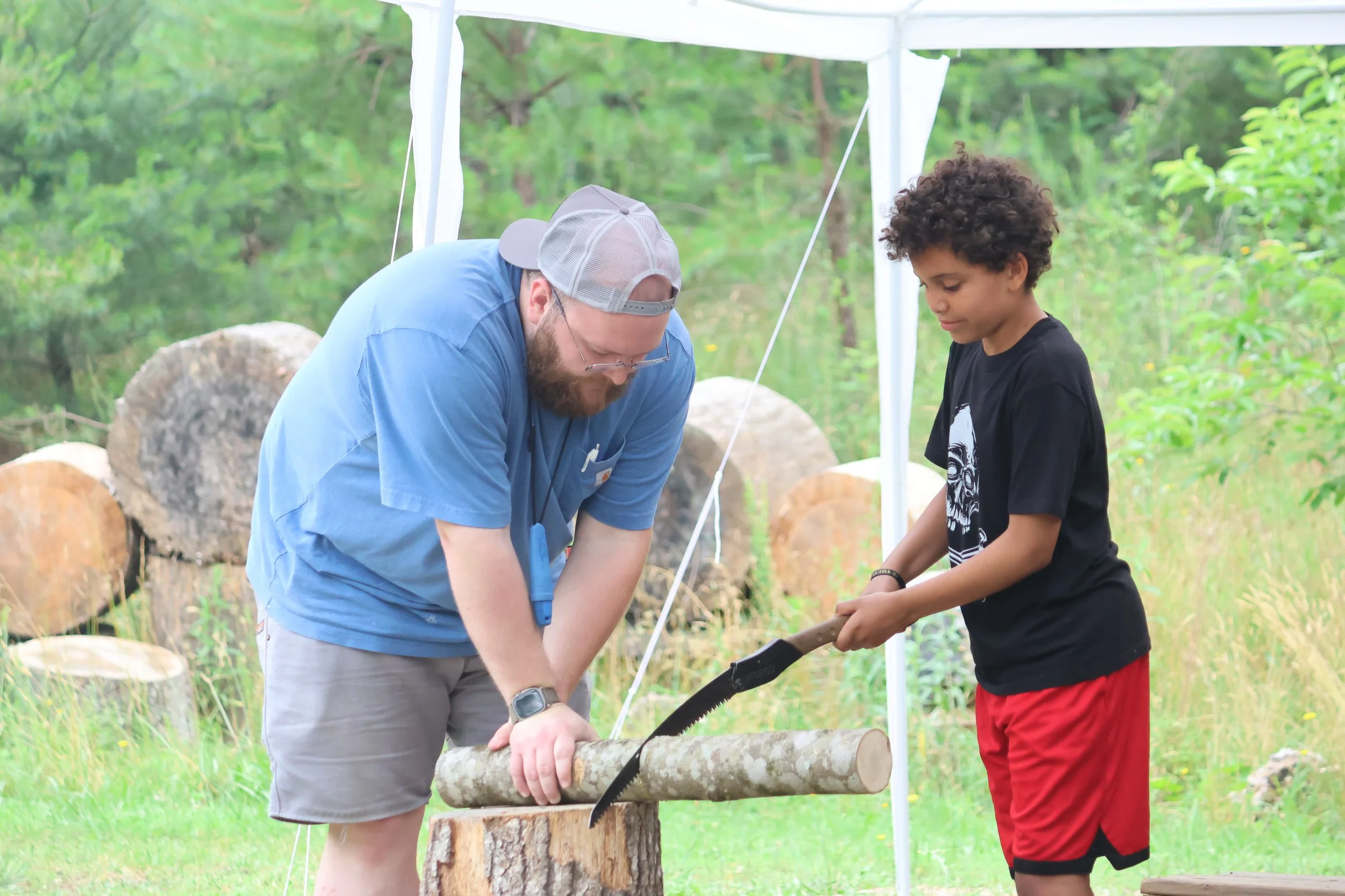 Counselor and Boy are safely sawing a log for a Bushcraft project. 