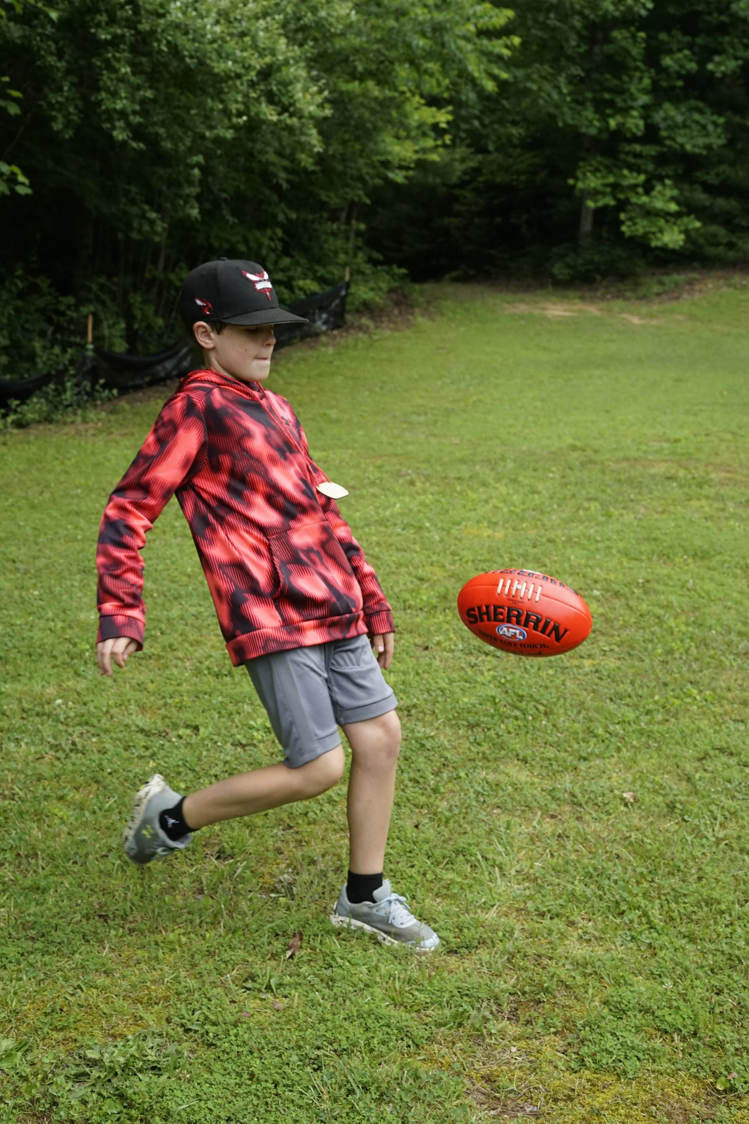 Camper punting the Sherrin Footy while learning Australian Football. 
