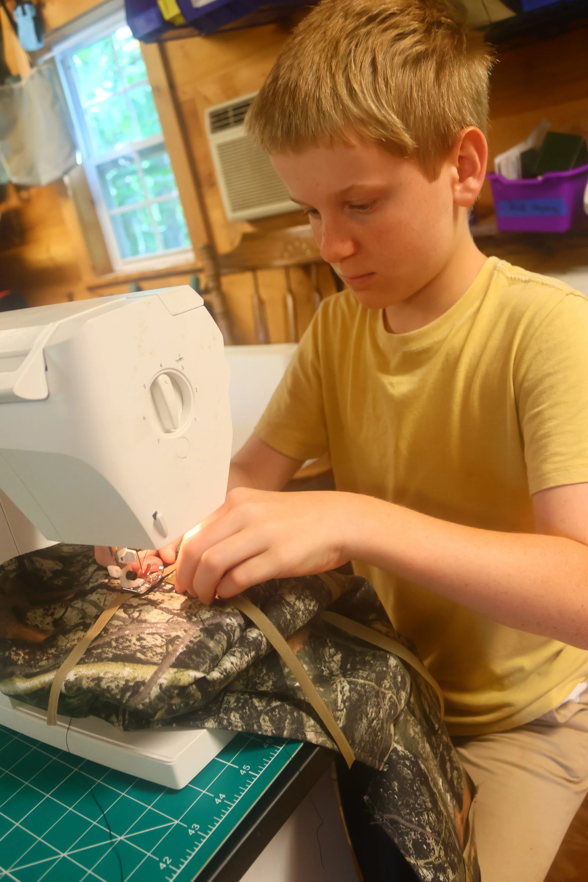 Camper sewing camouflage fabric on the machine at Arrowhead. 