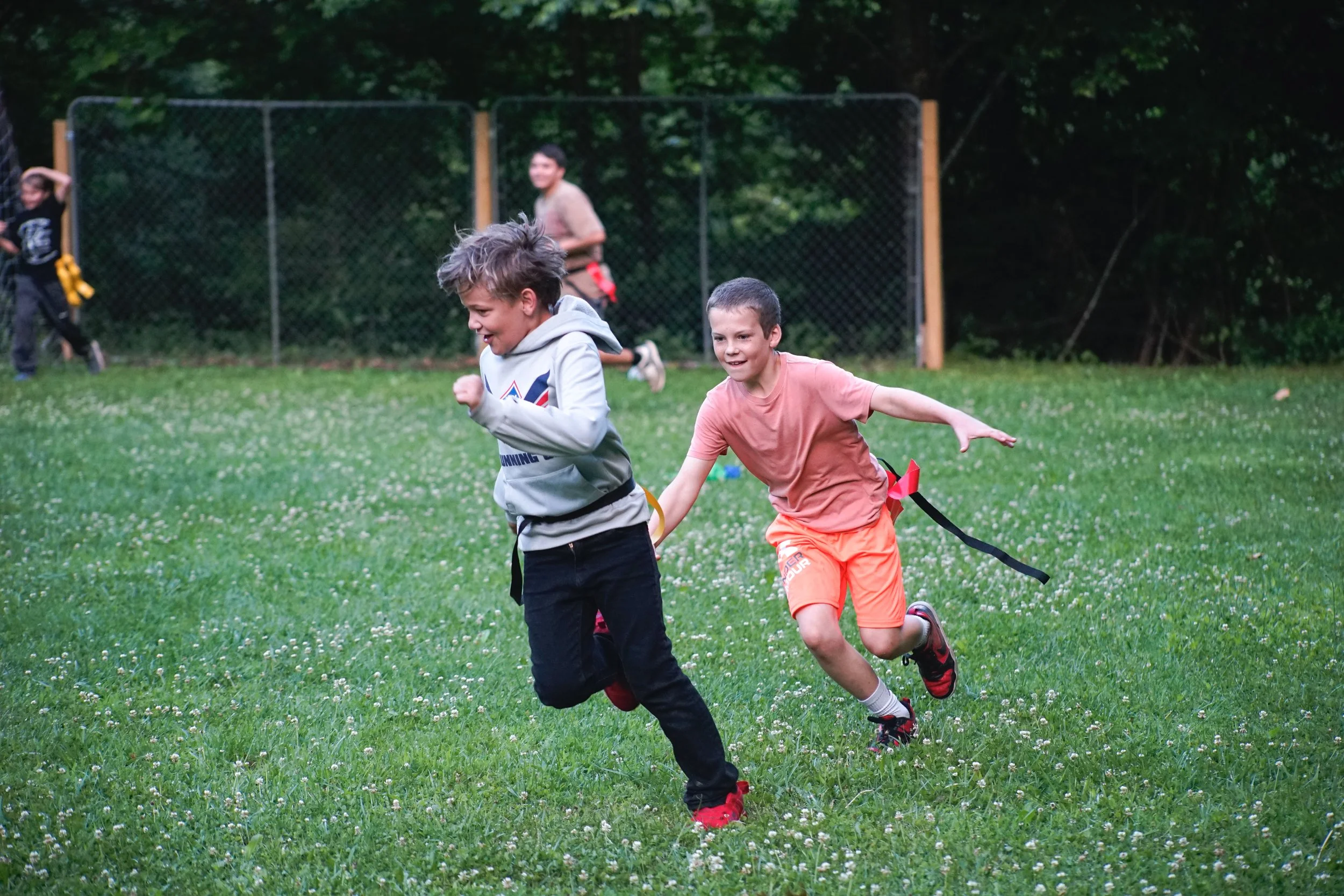Two sleepaway campers running around on the Camp Arrowhead Field in NC.
